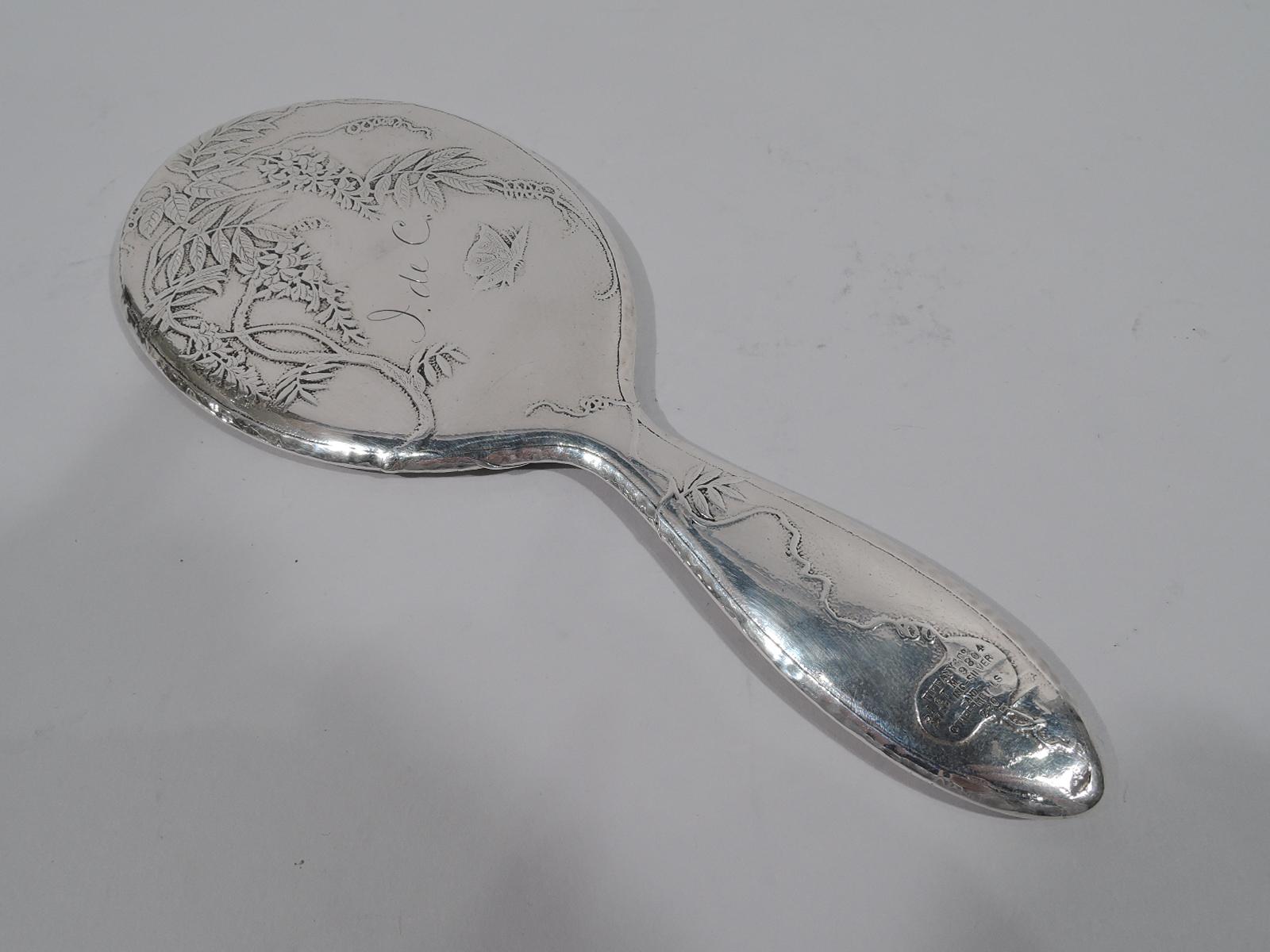 Japonesque sterling silver and mixed metal hand mirror. Made by Tiffany & Co. in New York, ca 1878. Curved and upward tapering handle and oval frame inset with beveled glass. Front has honeycomb hand hammering and is applied with modish insects