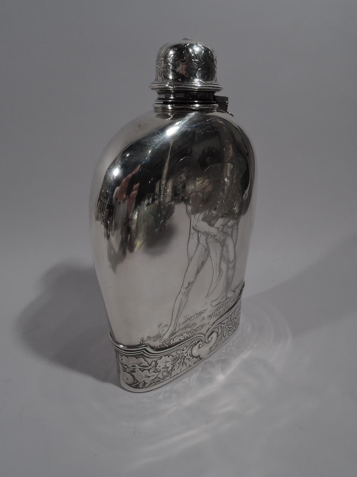 Large sterling silver flask made by Tiffany & Co. in New York. Arched top with hinged and cork-lined CAP. Acid-etched ornament. At bottom oak branches and fleurs de lys with reeded curvilinear border.

On front a pair of nude wrestlers heave and