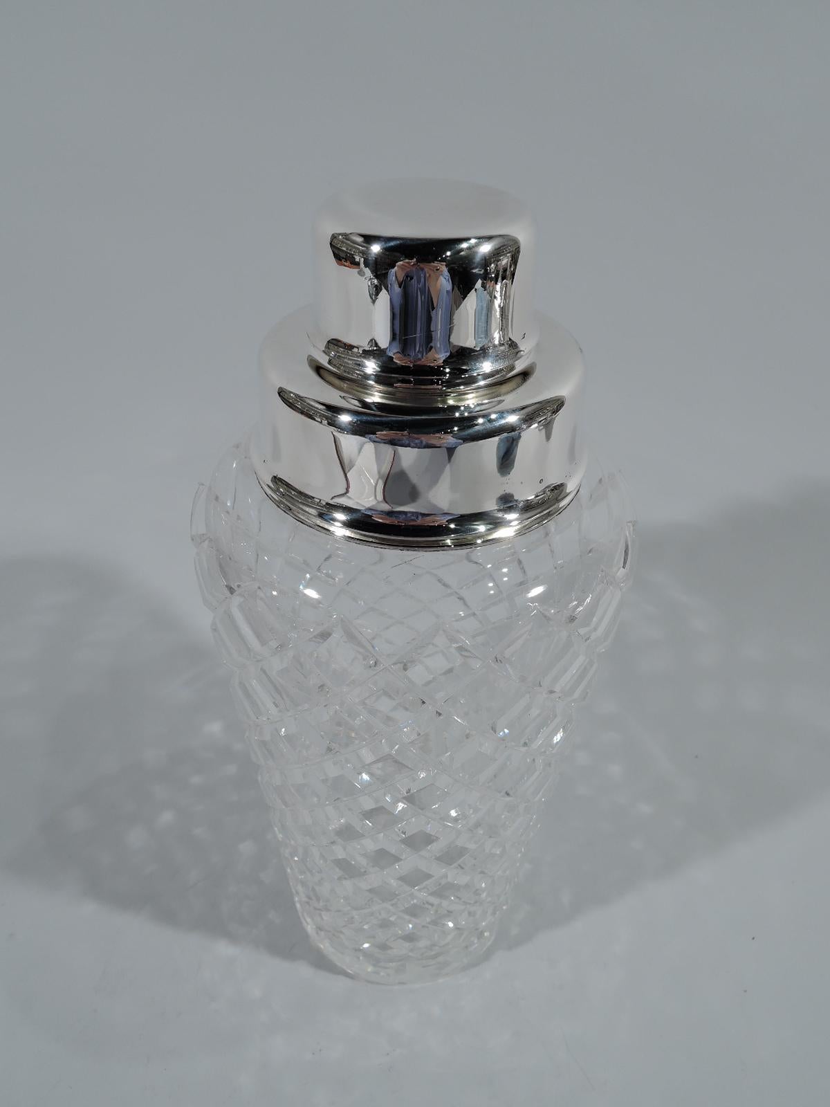 Mid-Century Modern sterling silver and cut-glass cocktail shaker. Made by Tiffany & Co. in New York. Clear glass cup with textural and easy-grip faceted diaper pattern. Short neck with sterling silver collar. Cover also sterling silver with built-in