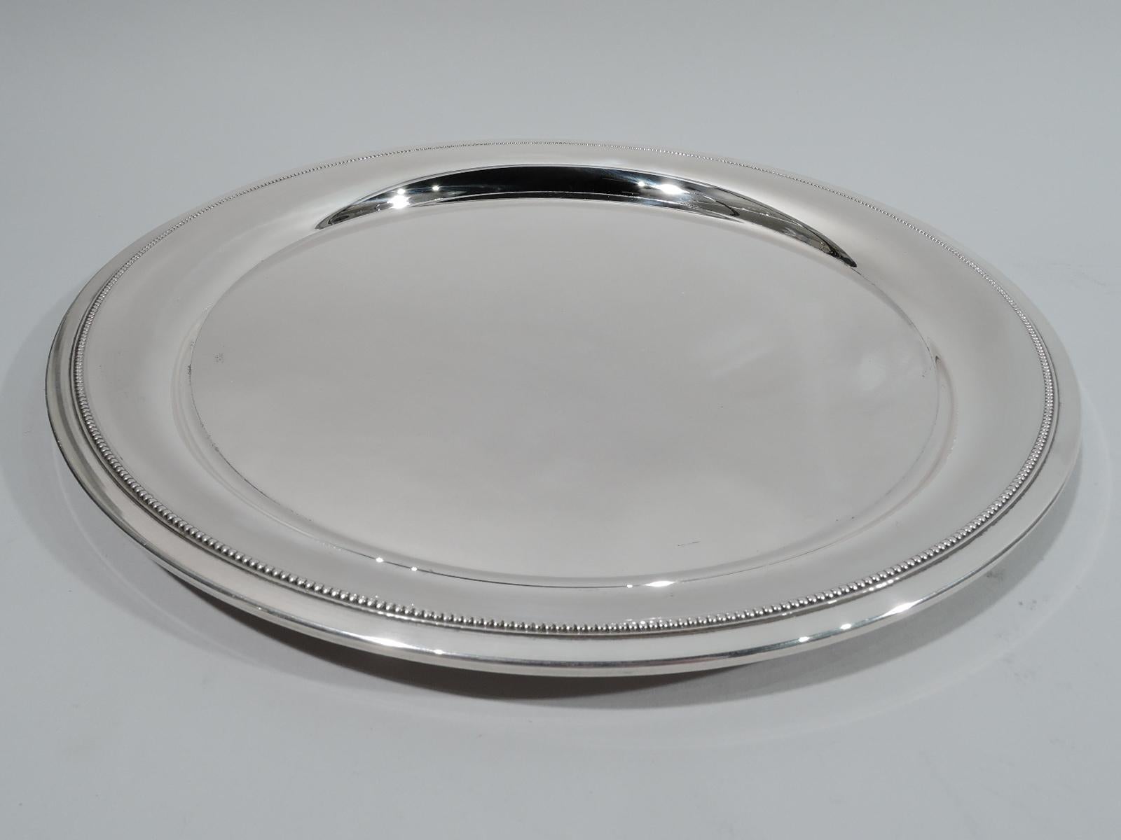 Mid-Century Modern Classical sterling silver tray. Made by Tiffany & Co. in New York. Round with deep well. Rim has finely beaded border. Fully marked including postwar pattern no. 23501. Weight: 22 troy ounces.