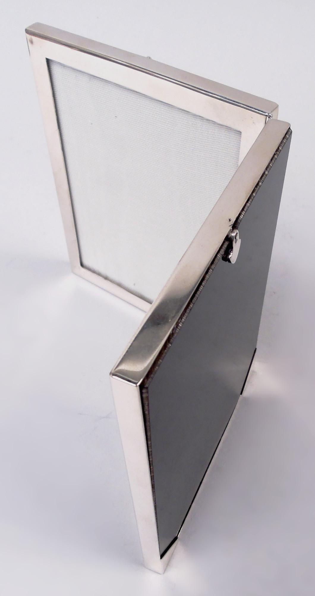 Cadre double en argent sterling de style moderne du milieu du siècle. Fabriqué par Tiffany & Co. à New York. Deux fenêtres à charnières, chacune dans un cadre plat et simple. Avec verre, doublure en soie et dos laminé pour une présentation