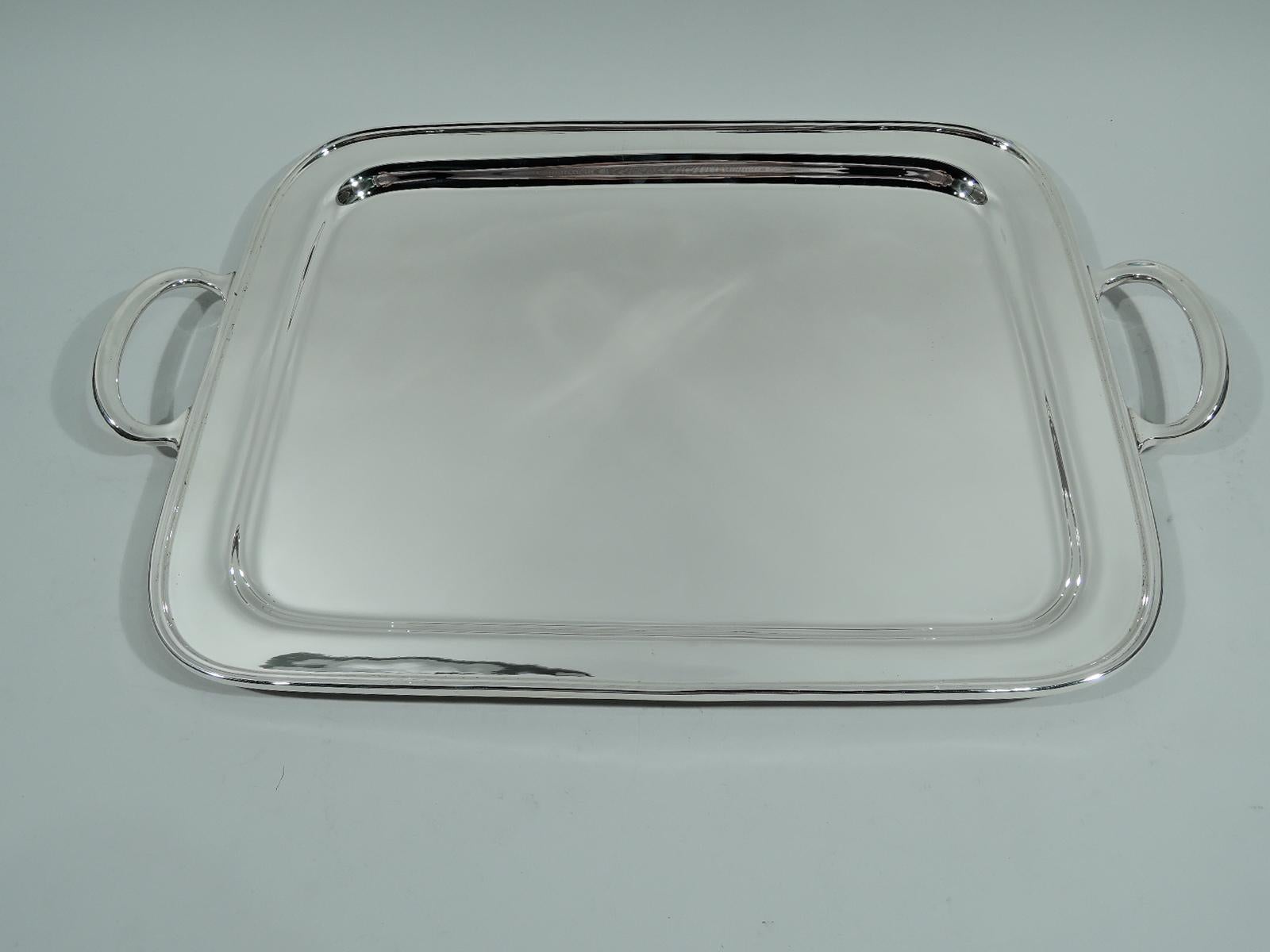 Mid-Century Modern sterling silver tray. Made by Tiffany & Co. in New York. Rectangular with curved corners, molded rim, and well. Mounted c-scroll end handles. Fully marked including postwar pattern no. 25558. 

Large overall dimensions: H 1 1/2