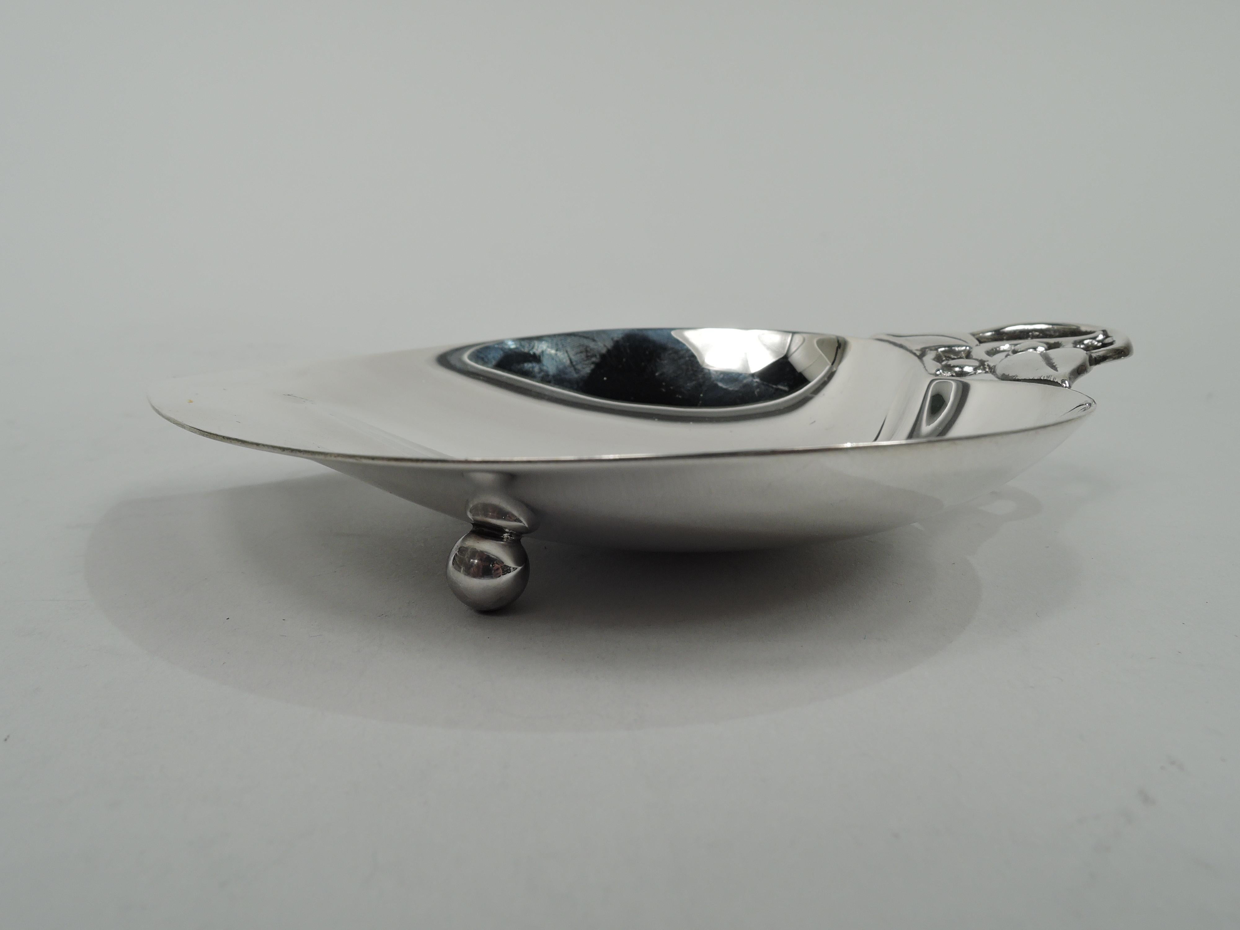 Mid-Century Modern sterling silver dish. Made by Tiffany & Co. in New York. Abstract and asymmetrical apple with scrolled stem and leaves. Rests on two ball supports. Fully marked including maker’s stamp, pattern no. 22885 (first produced in 1940),