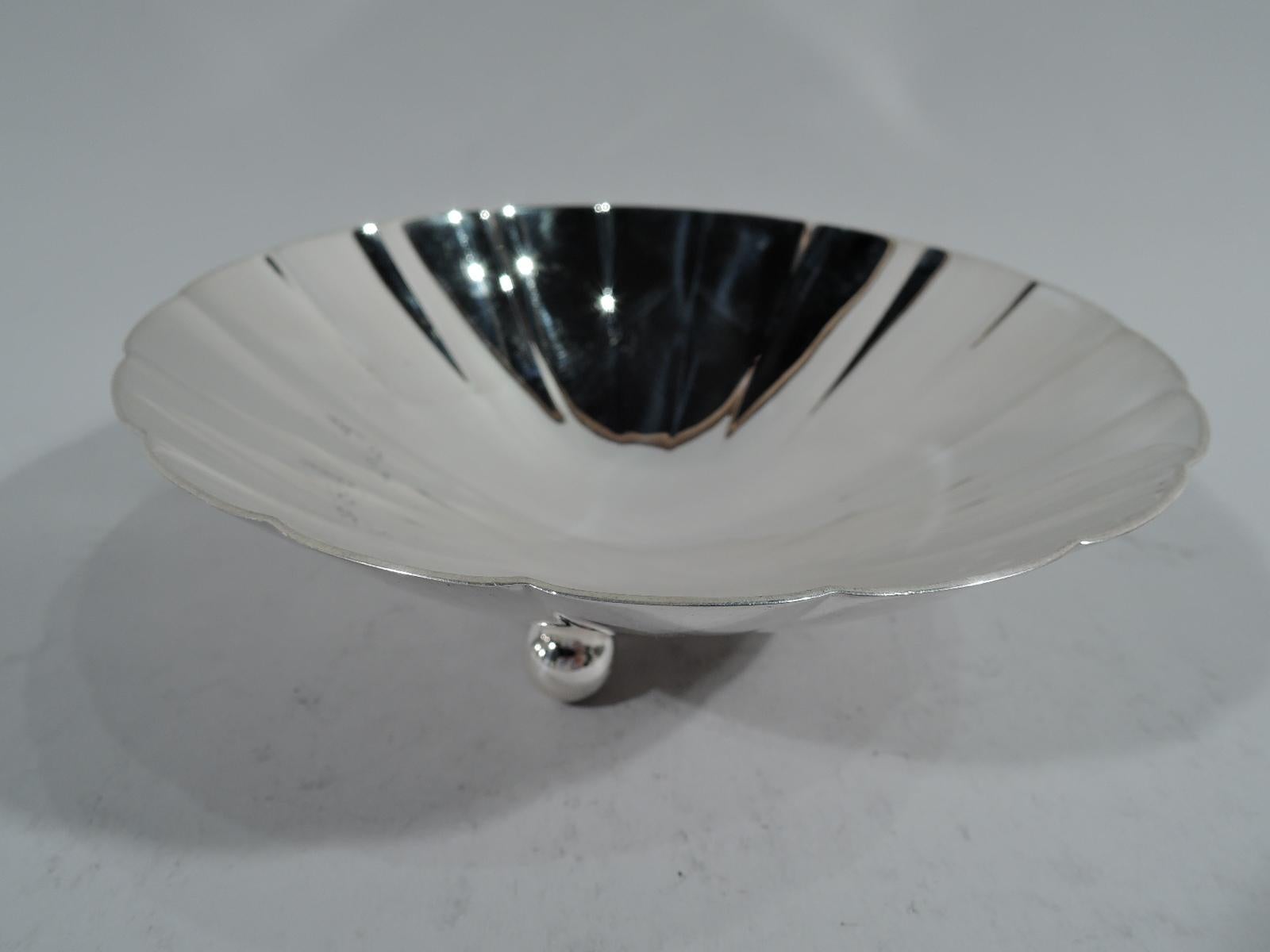 Midcentury Modern sterling silver bowl. Made by Tiffany & Co. in New York. Shallow cone with soft fluting and scalloped rim. Three ball supports. Hallmark includes pattern no. 22673 and director’s letter M (1947-56). Weight: 7.5 troy ounces.