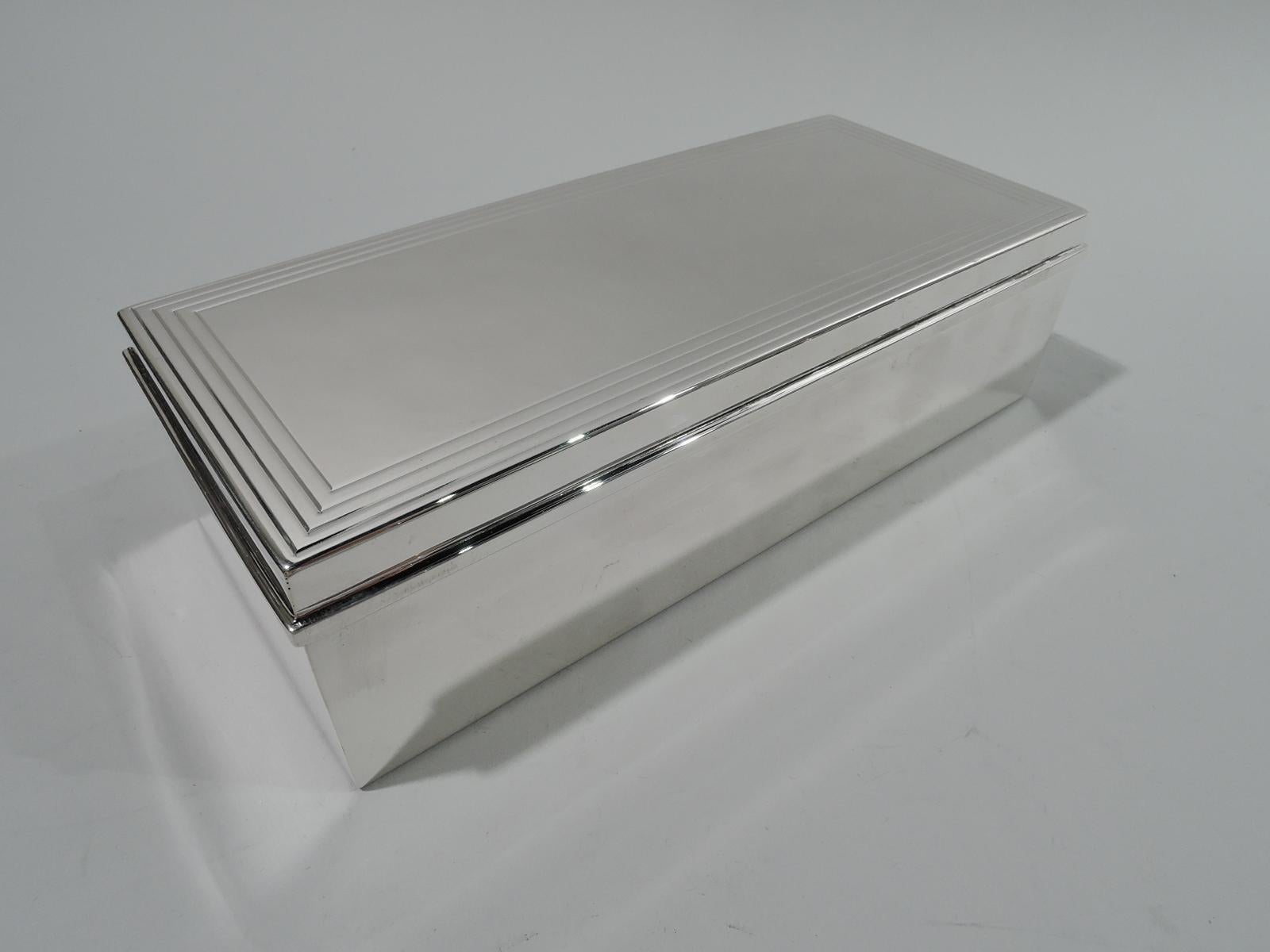Mid-Century Modern sterling silver box. Made by Tiffany & Co. in New York. Rectangular with straight sides. Cover flat and hinged with molded rim. Cover top has wraparound linear border. Box interior cedar lined and partitioned. Cover interior gilt.