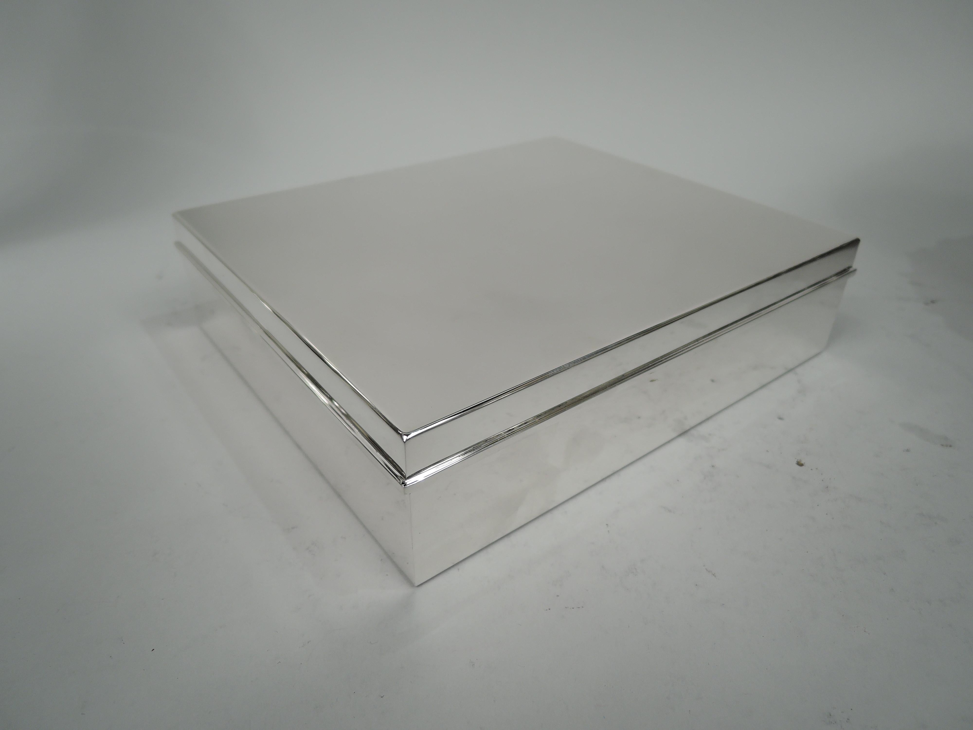 Mid-Century Modern sterling silver box. Made by Tiffany & Co. in New York. Rectangular with straight sides. Cover flat and hinged with flat molded rim. Box interior cedar lined and partitioned. Box interior gilt washed. Fully marked including