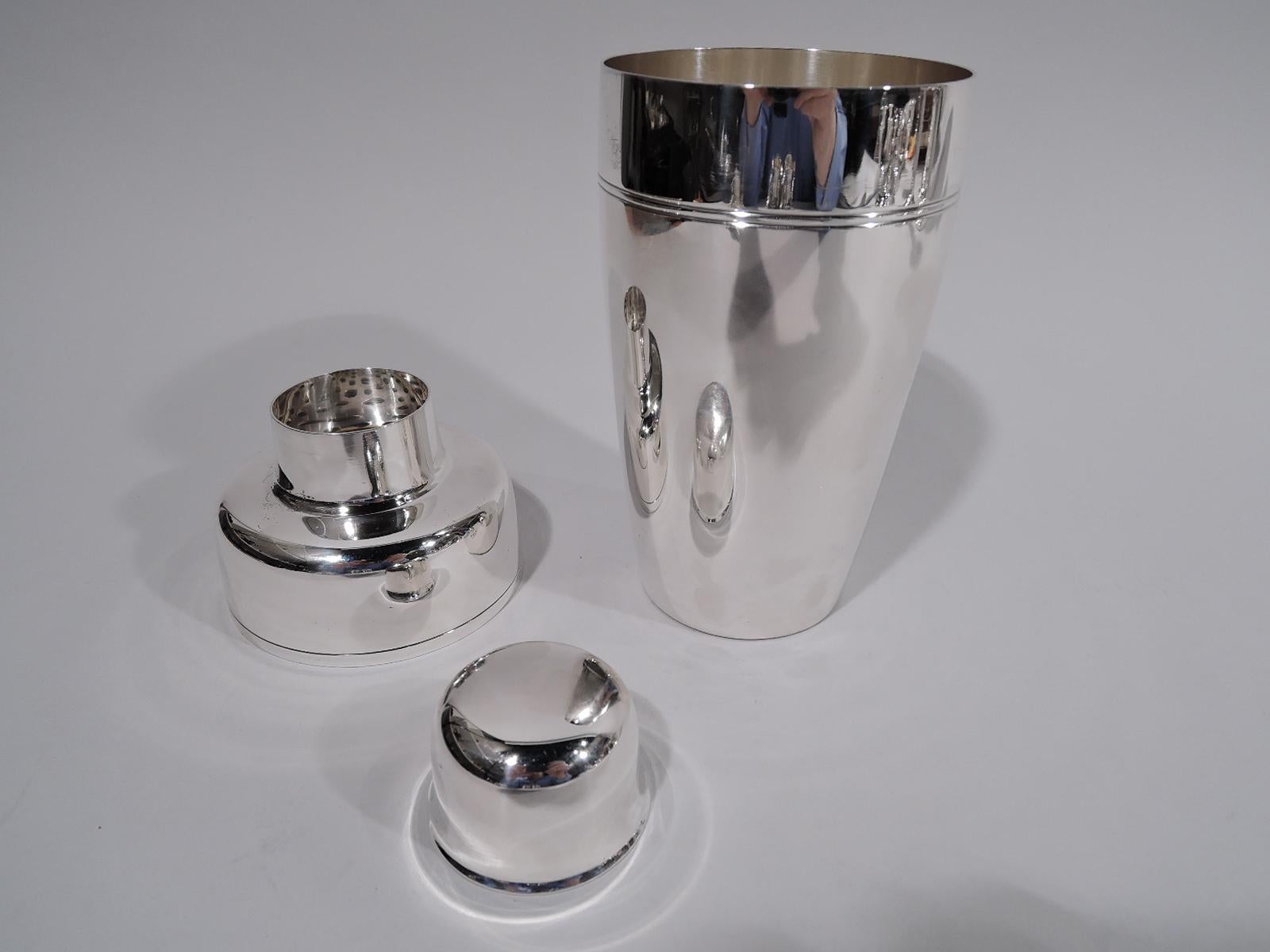 Mid-Century Modern sterling silver cocktail shaker. Made by Tiffany & Co. in New York, ca 1947. The classic bullet form comprising tapering cup, curved shoulders, and central spout with built-in strainer. Cap has flared rim. Spare with incised
