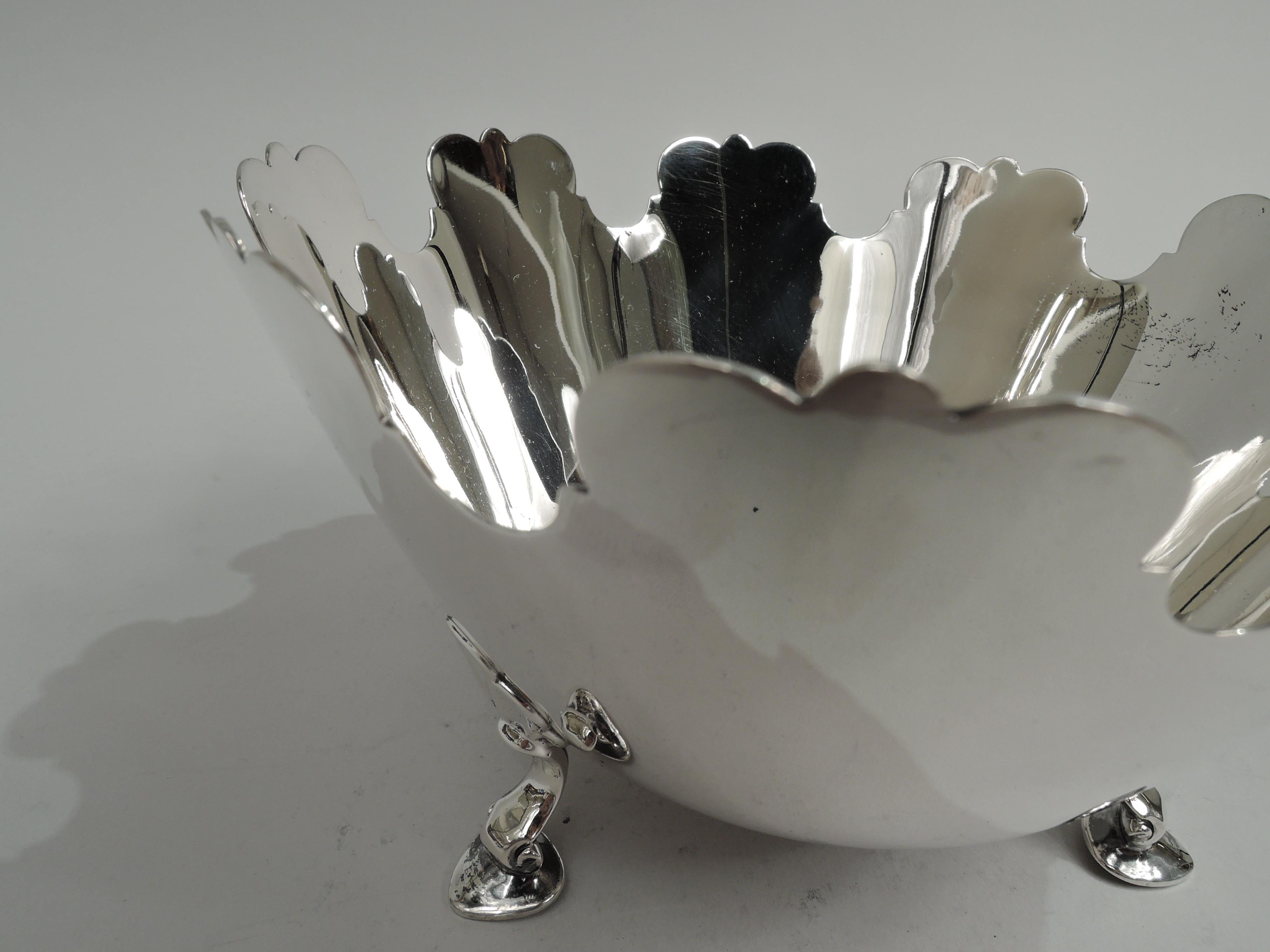 Mid-Century Modern sterling silver bowl. Made by Tiffany & Co. in New York. Tapering sides and curved bottom on stylized leaf-mounted hoof supports. Monteith-style rim with alternating trefoils and curvilinear dips. Fully marked including maker’s