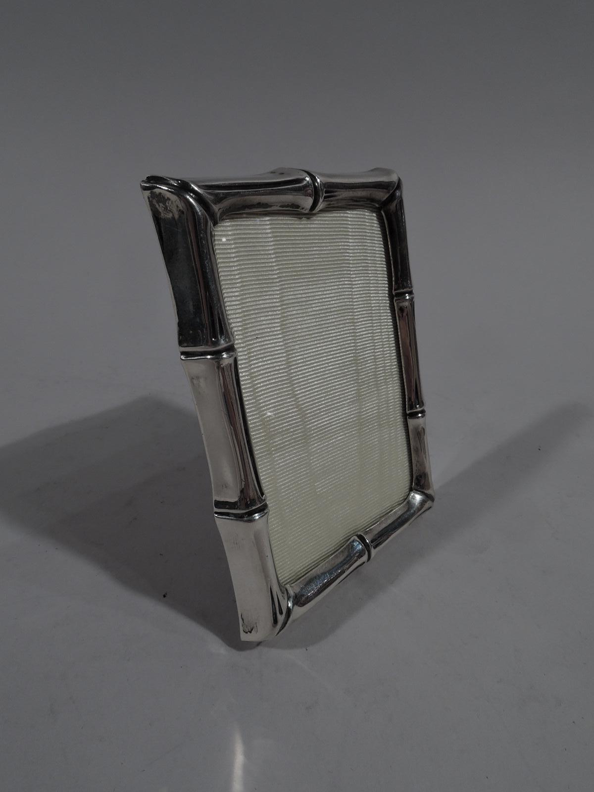 Mid-Century Modern sterling silver novelty picture frame. Made by Tiffany & Co. in New York. Rectangular window in bamboo-style surround. With glass, silk lining, laminate back, and fixed sterling silver support. For portrait (vertical) display.