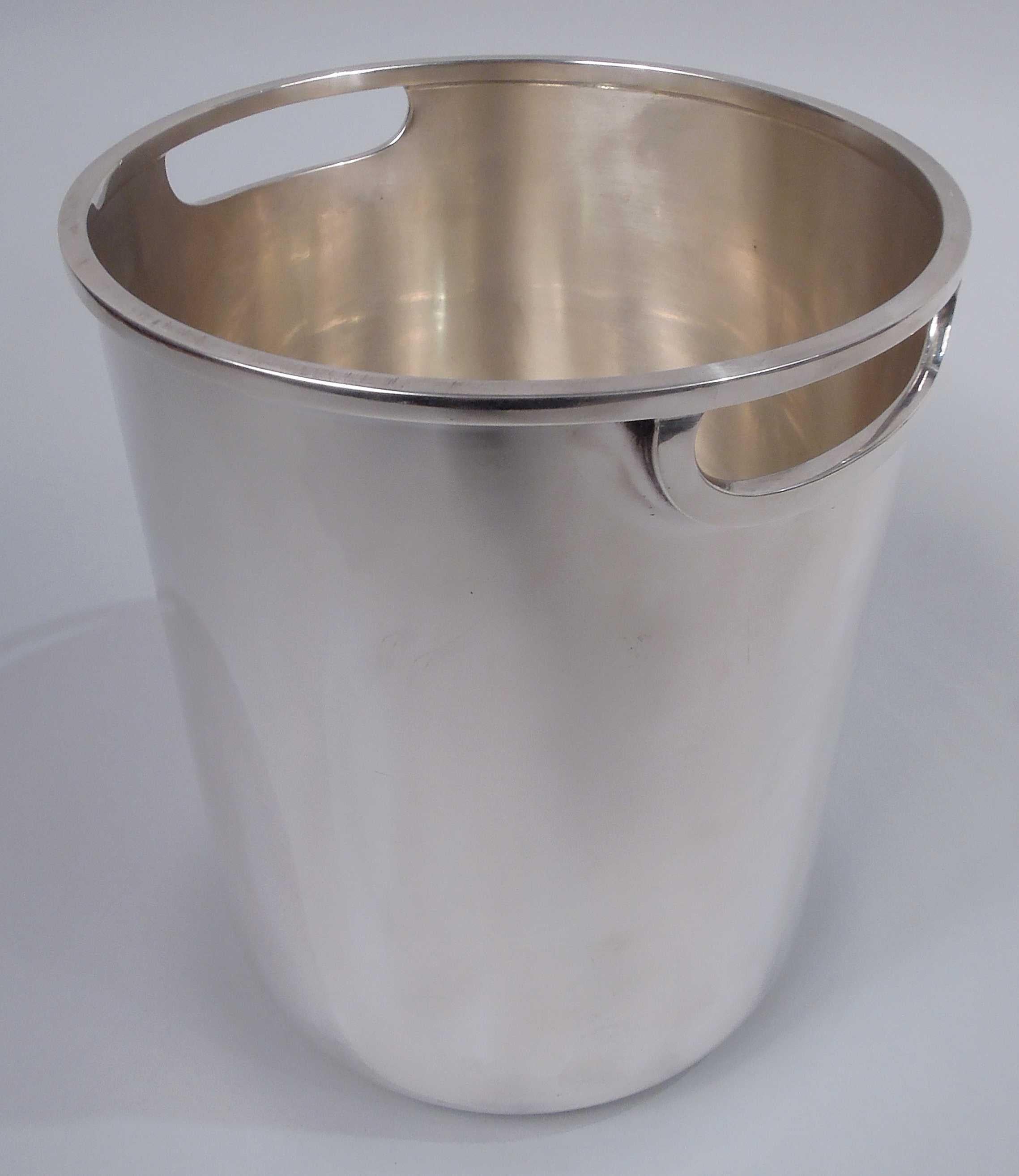 Midcentury Modern sterling silver wine cooler. Round with straight sides and curved bottom. Cutout lunette side handles have rectilinear molding as does mouth rim. Sleek and capacious. Marked “Tiffany & Co. / Sterling Silver”. Heavy weight: 48.3