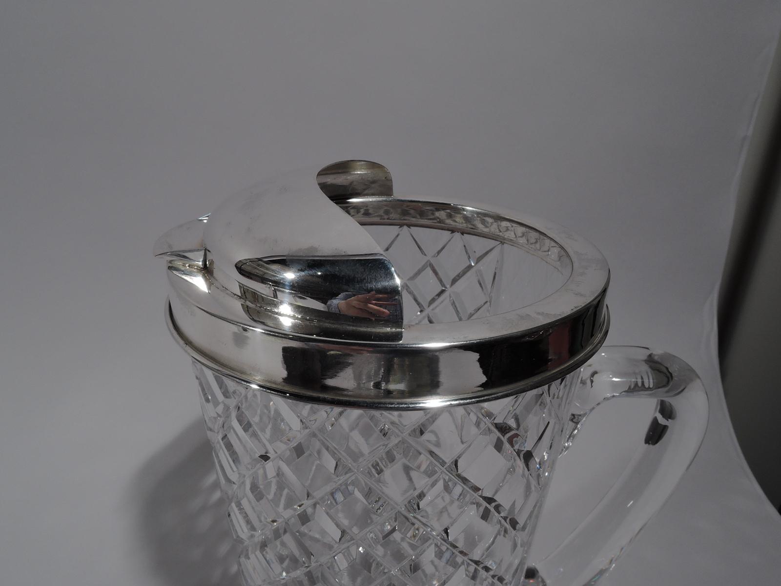 Mid-Century Modern sterling silver and glass bar pitcher. Retailed by Tiffany in New York. Clear glass with straight and tapering sides, and C-scroll handle. All-over raised diaper pattern except back, which is plain. Sterling silver collar with