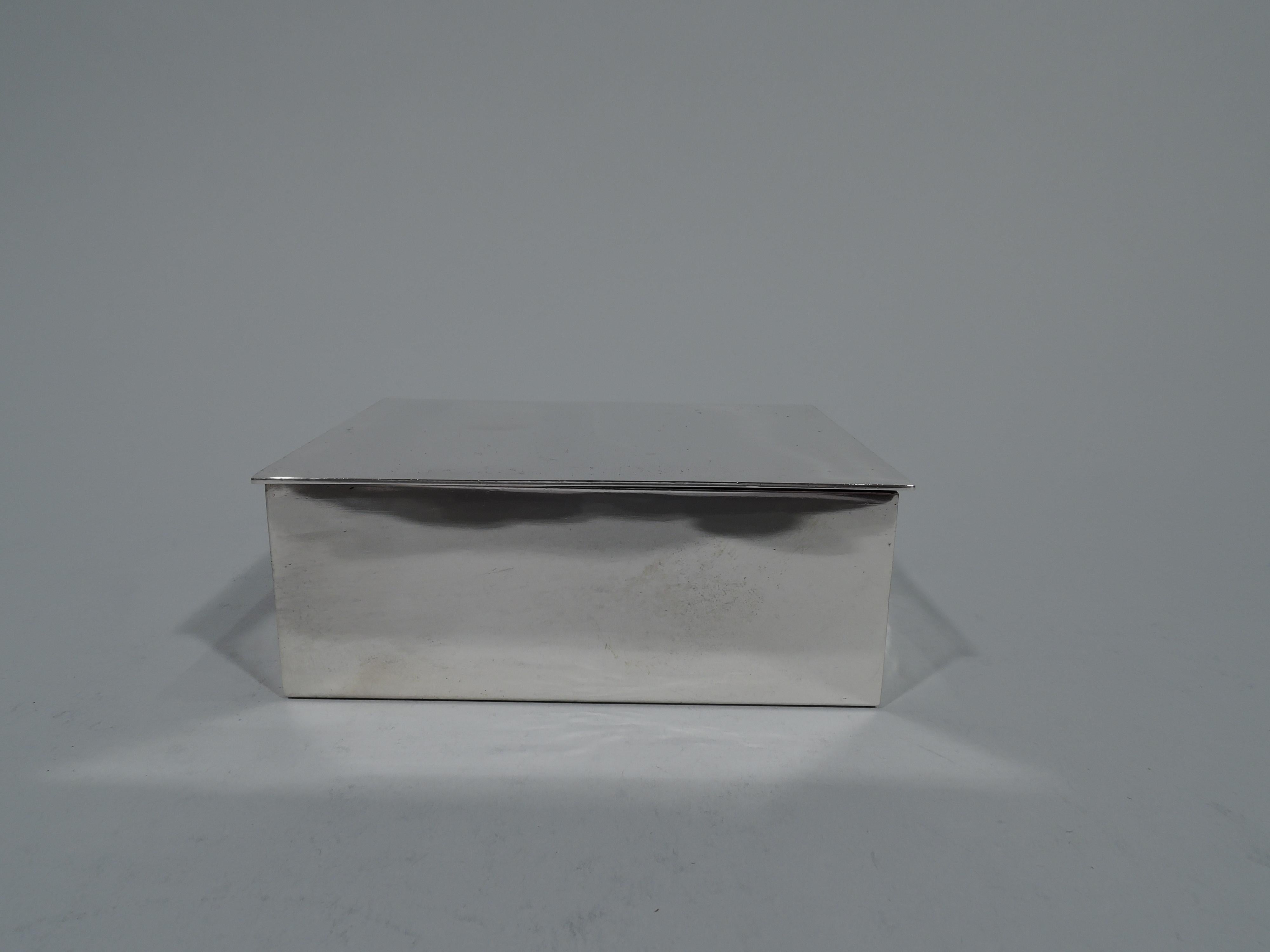 Modern and compact sterling silver box. Made by Tiffany & Co. in New York. Rectangular with flat, hinged, and overhanging cover. Box interior cedar lined. Hallmark includes postwar pattern no. 23325 and director’s letter L (1956-circa 1965). Gross