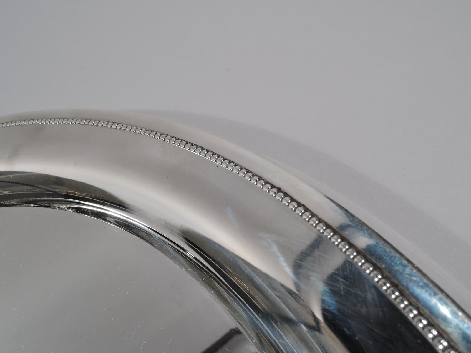 Modern Classical sterling silver tray. Made by Tiffany & Co. in New York. Round with deep well. Rim has finely beaded border. Fully marked including postwar pattern no. 23501. Weight: 21 troy ounces.