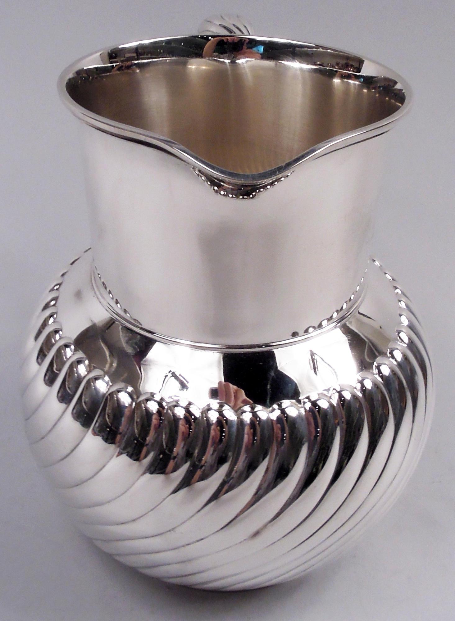 Pichet d'eau classique moderne en argent sterling. Bol globulaire, col en forme de tambour, bec à petite lèvre et poignée C.C.C. Cannelures torsadées sur le bol et la poignée. Un design audacieux et dynamique des années 70, c'est-à-dire des années