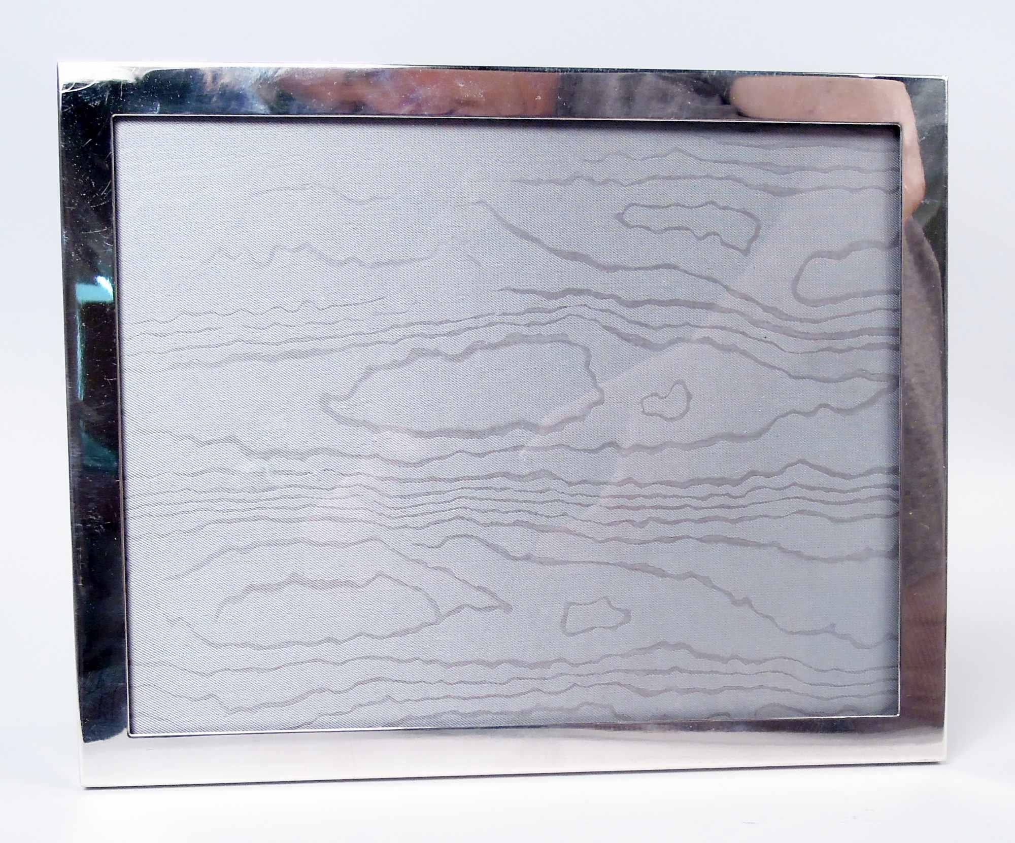 Moderner Rahmen aus Sterlingsilber. Wiederverkauft von Tiffany & Co. in New York. Einfacher und flacher rechteckiger Rahmen. Mit Glas, Seidenfutter und Rückwand aus Holzlaminat und aufklappbarer Staffelei für Hochformat (vertikal) oder Querformat