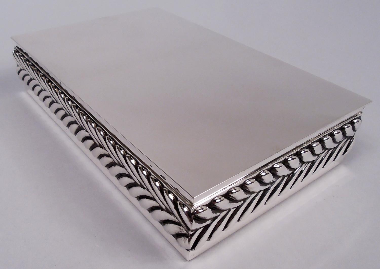 Modernes Döschen aus Sterlingsilber aus der Jahrhundertmitte. Hergestellt von Tiffany & Co. in New York. Rechteckig mit flachem und aufklappbarem Deckel. Die Seiten und die Vorderseite sind mit einem umlaufenden Flachreliefband aus ineinander