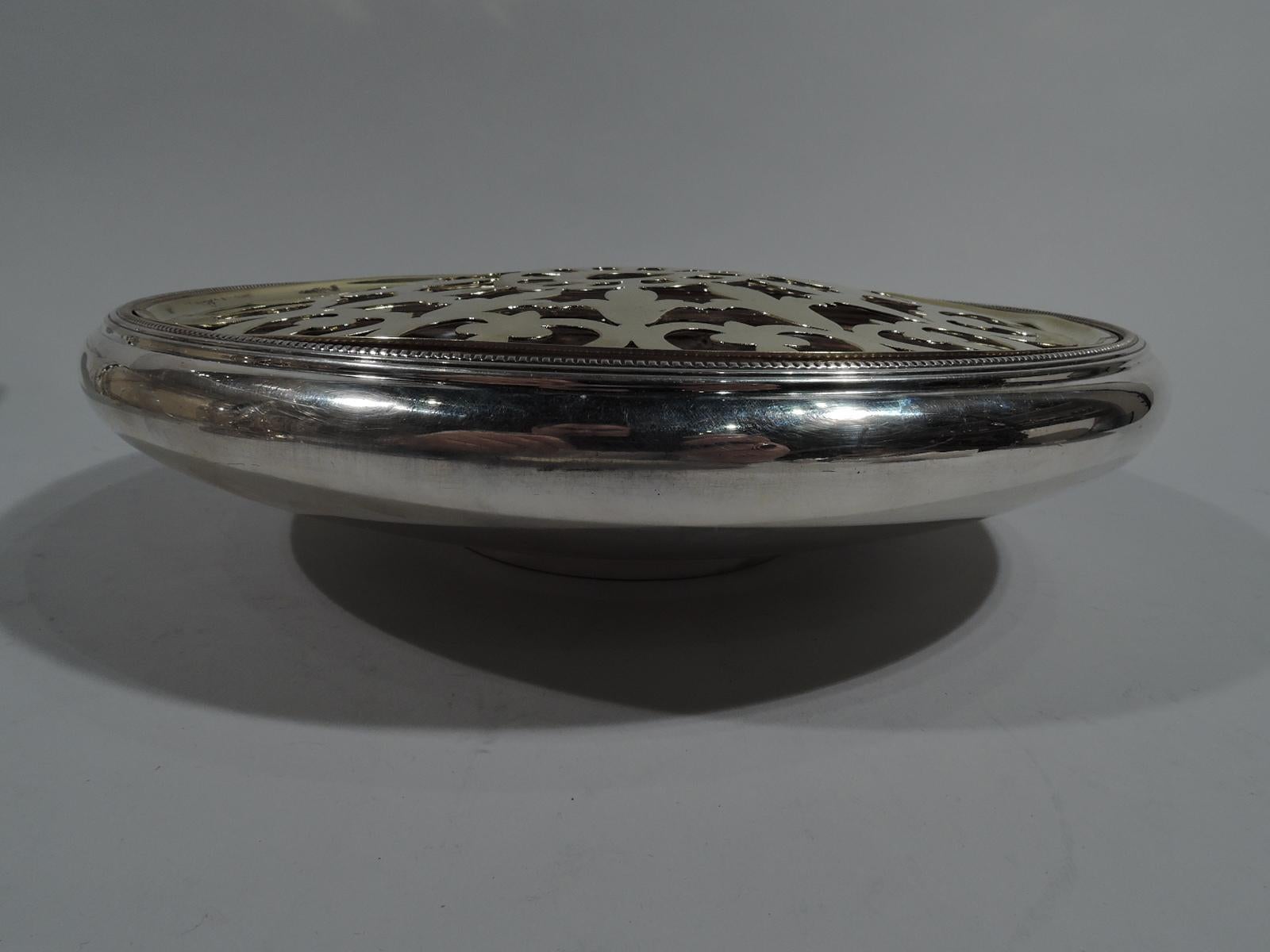 Modern sterling silver flower bowl. Made by Tiffany & Co. in New York, circa 1915. Round and shallow with short straight foot and wide mouth with dentil rim. With brass frog with open floral ornament: Central petal flower surrounded by two rows of