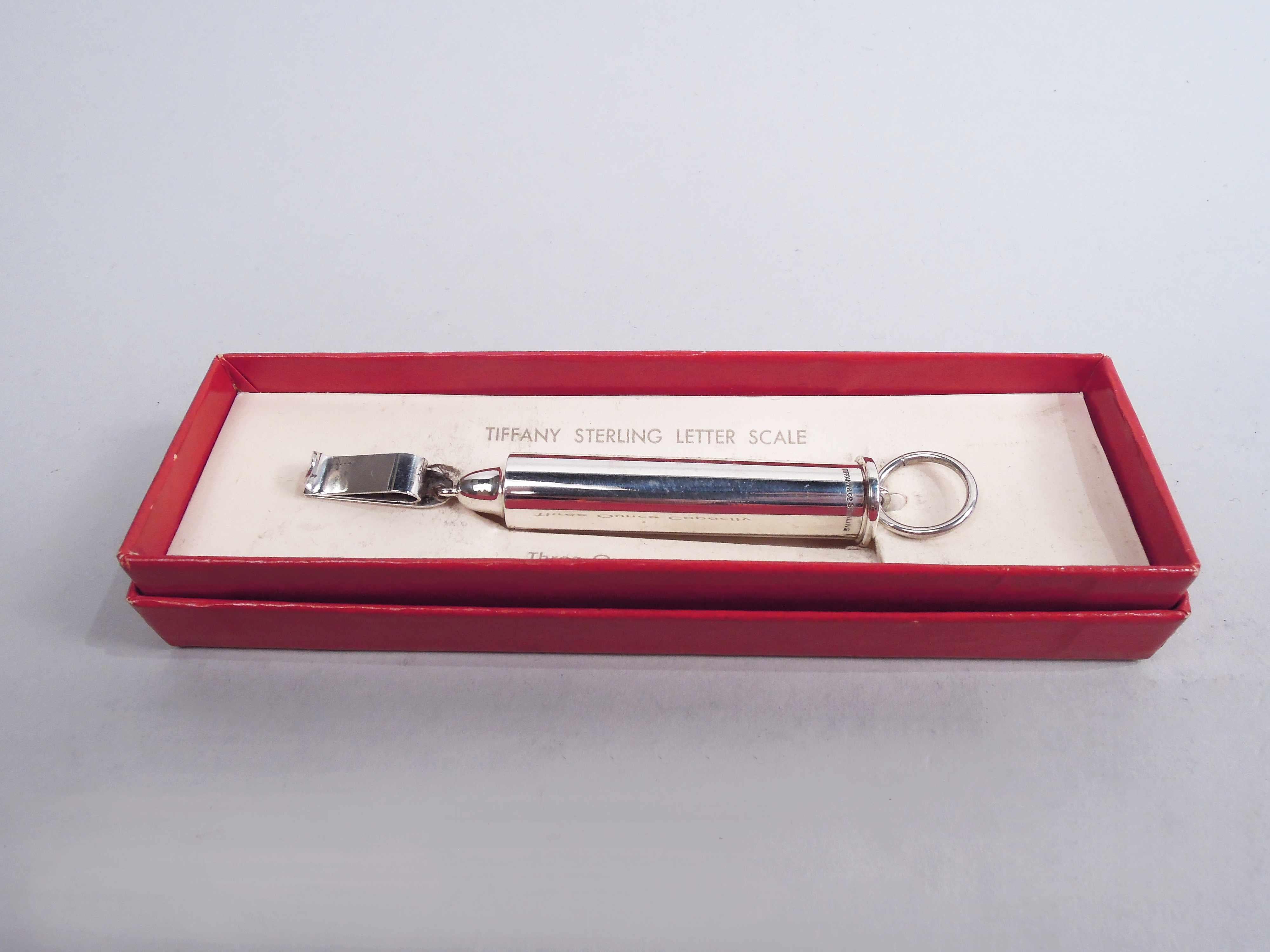 Modern sterling silver portable postage scale, ca 1930. Retailed by Tiffany & Co. in New York. Cylindrical with loose-mounted clip; top ring loose-mounted to pullout counterweight stick with engraved units in ounces. Measures a maximum of 3 ounces.