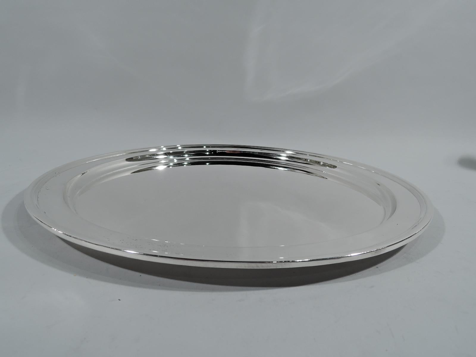 Modern sterling silver serving tray. Made by Tiffany & Co. in New York. Round with well, tapering shoulder, and molded rim. Hallmark includes pattern no. 20221 (first produced in 1923) and director’s letter m (1907-47). Weight: 37.5 troy ounces.