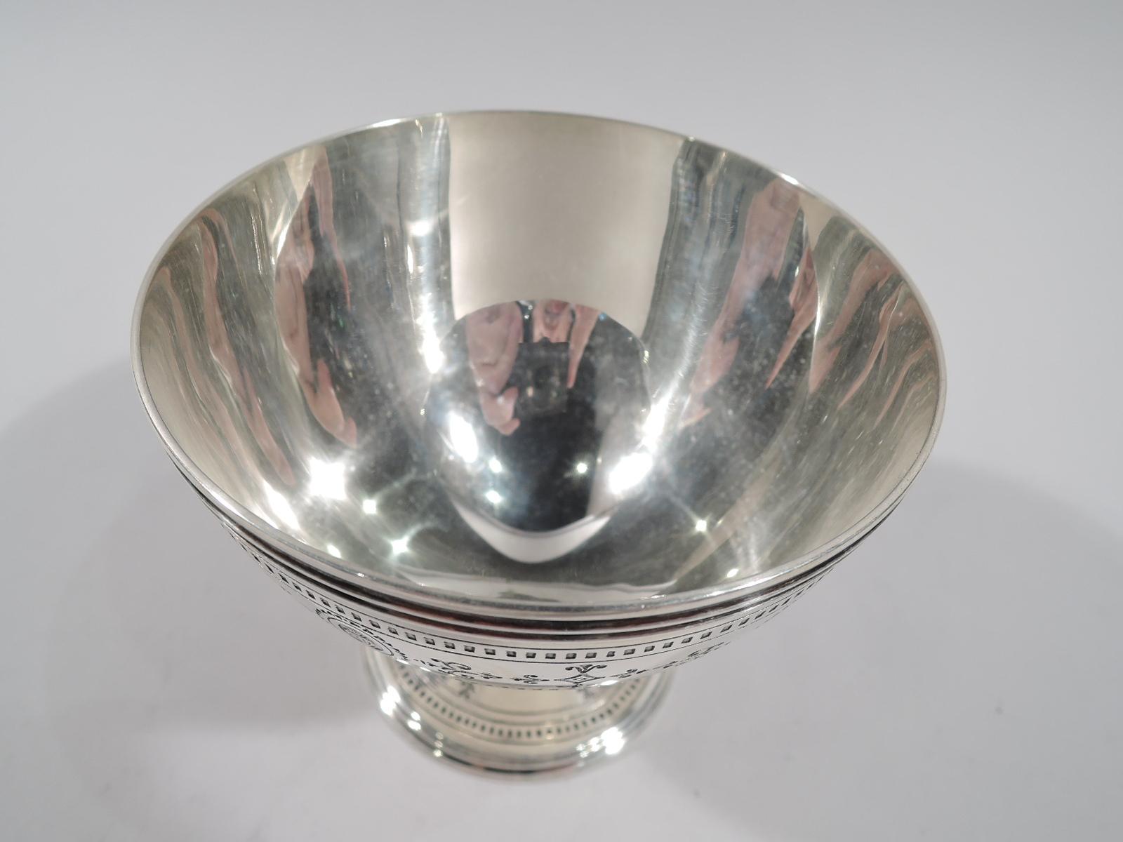 Neoclassical sterling silver sugar bowl. Made by Tiffany & Co. in New York. Curved and tapering sides with reeded rim and stepped and raised foot. Engraved and acid-etched band with urn-inset oval wreathes between dentil borders. Fully marked