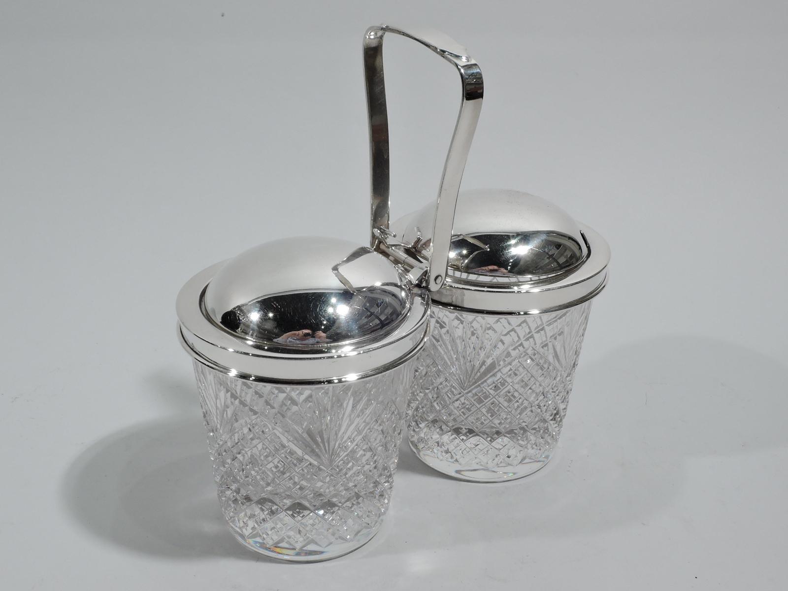 Old-fashioned sterling silver and glass double jam jar, ca 1950. Retailed by Tiffany & Co. in New York, ca 1950. Two jars, each with straight and tapering sides and raised diaper and fern pattern. Sterling silver collars joined by mount with open