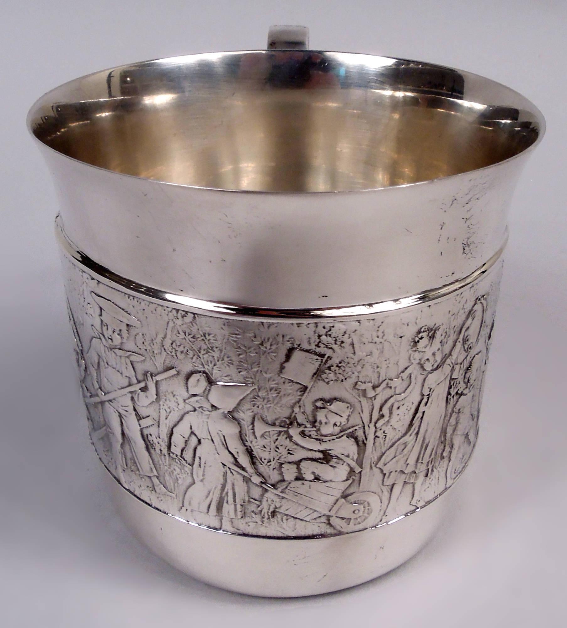 Tazza per bambini in argento sterling vecchio stile. Realizzato da Tiffany & Co. a New York. Fianchi dritti e manico lobato a c-scroll. Fregio a basso rilievo della parata dei bambini: un'allegra processione di ragazzi e ragazze che suonano le