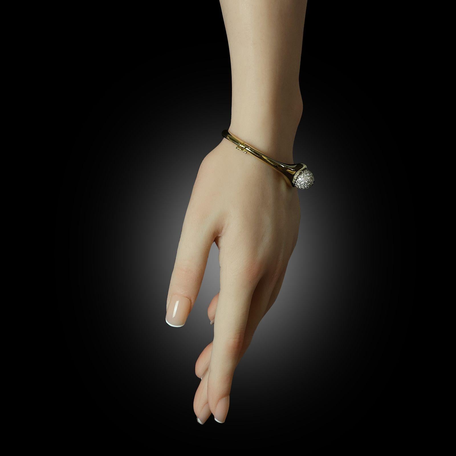 Un bracelet en or et diamants conçu par Paloma Picasso pour Tiffany & Co. vers 1980, le bracelet solide en or jaune 18ct avec un profil ovale, une ouverture à charnière sur le côté et une zone plus large se rétrécissant vers le sommet central qui