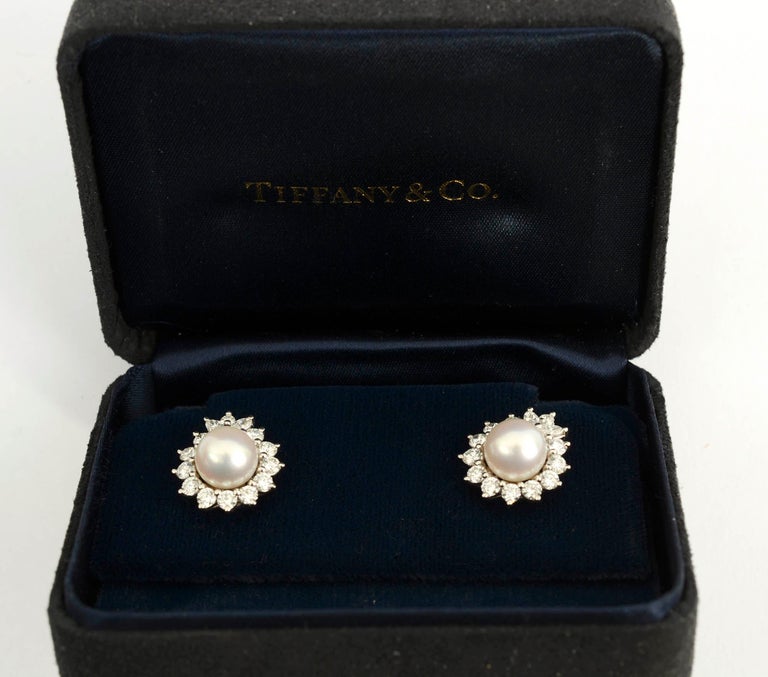 Classic earrings by Tiffany with a pearl surrounded by diamonds. Each earring has an 8.5 mm pearl surrounded by 14 diamonds. The total carat weight is approximately 1.6 carats. Stones are G-H color.
These elegant  earrings are platinum with post