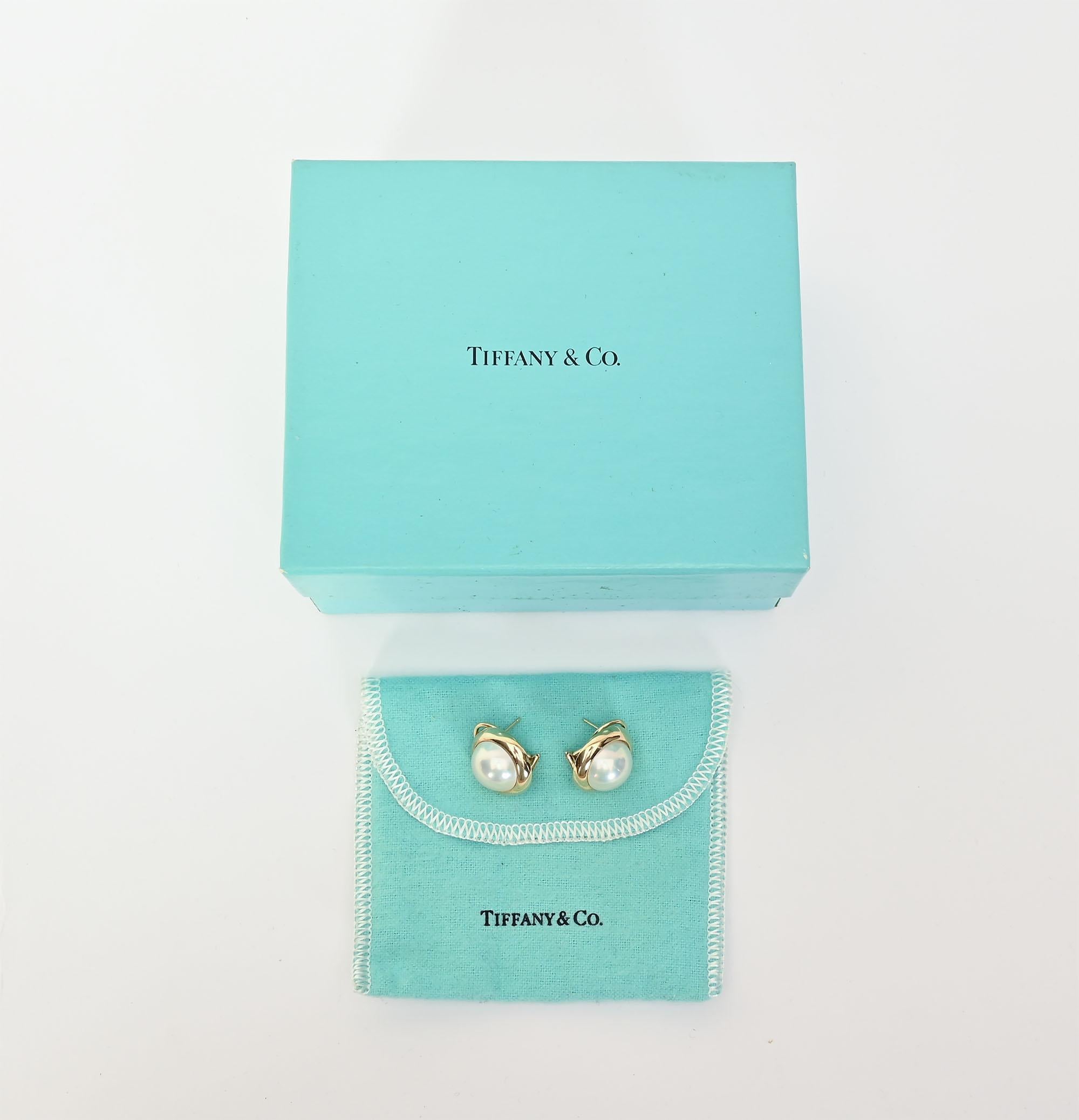 Classic 14 karat pearl earrings by Tiffany that are suitable for a woman of any age. The pearls are 14 mm set in a wide gold collar. Backs are clips and posts. The earrings are sold with the original Tiffany cloth case and box.