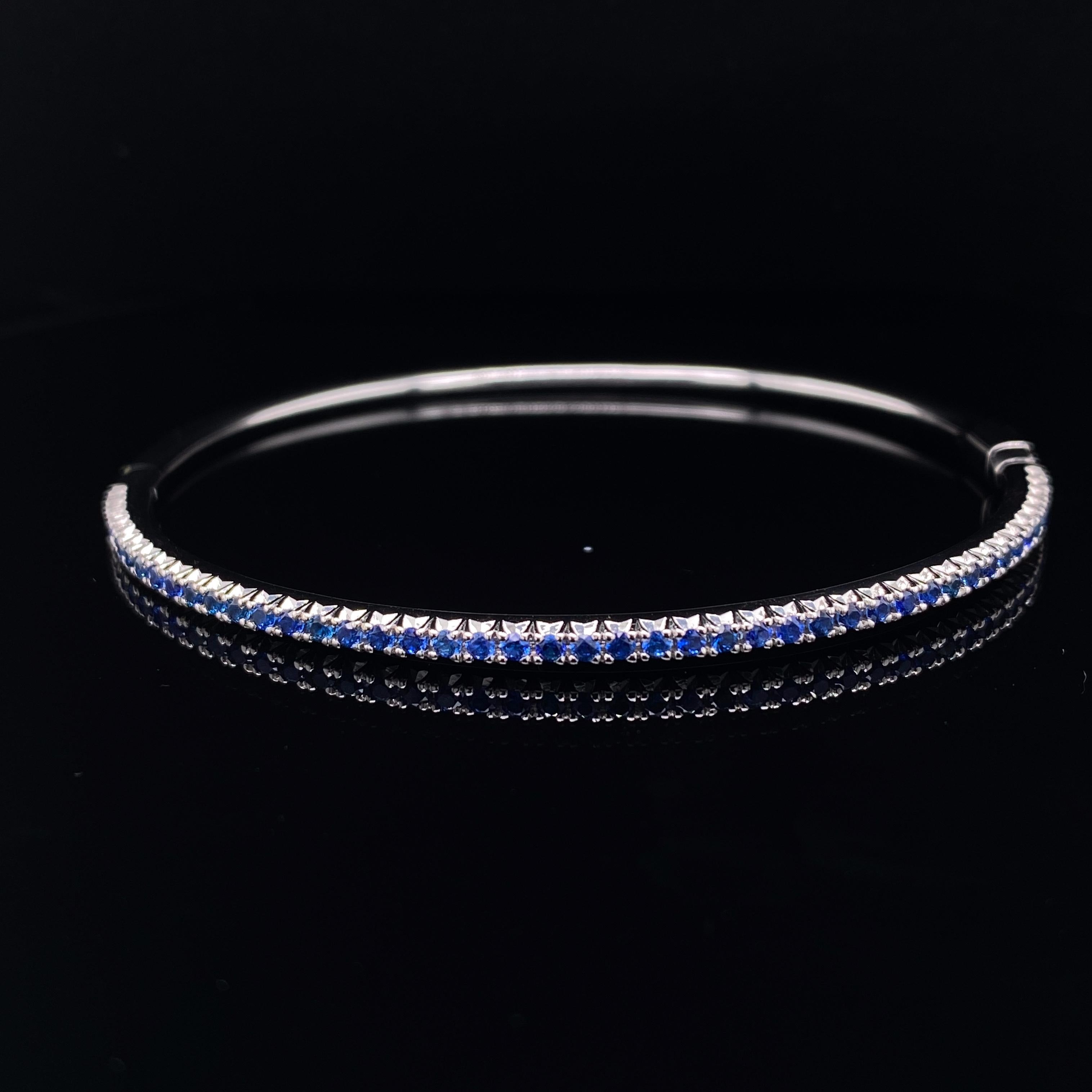 A Tiffany sapphire bangle in 18 karat white gold.

This slim elegant gold bangle bracelet has a hinged fitting and is claw set to its top half with rich, bright deep hued sapphires.

Its pared back design places all focus on the sapphires, allowing