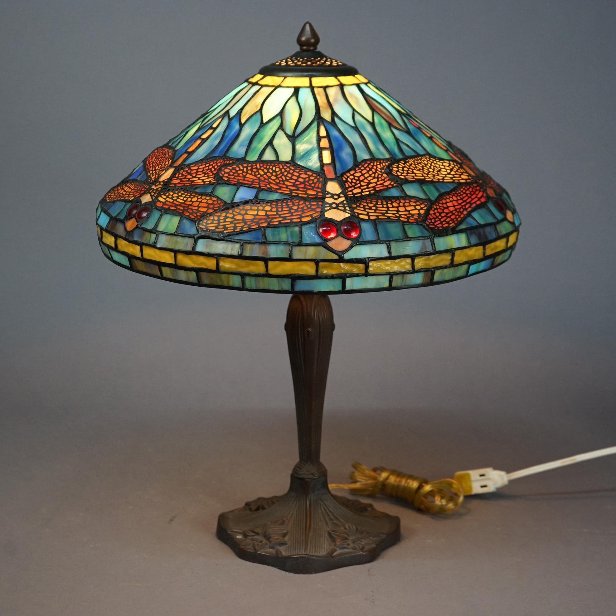 A table lamp in the manner of Tiffany offers leaded stained and jeweled glass dragonfly shade over single socket cast base, 20th century.

Measures- 21.5' 'H x 16'' W x 16'' D.