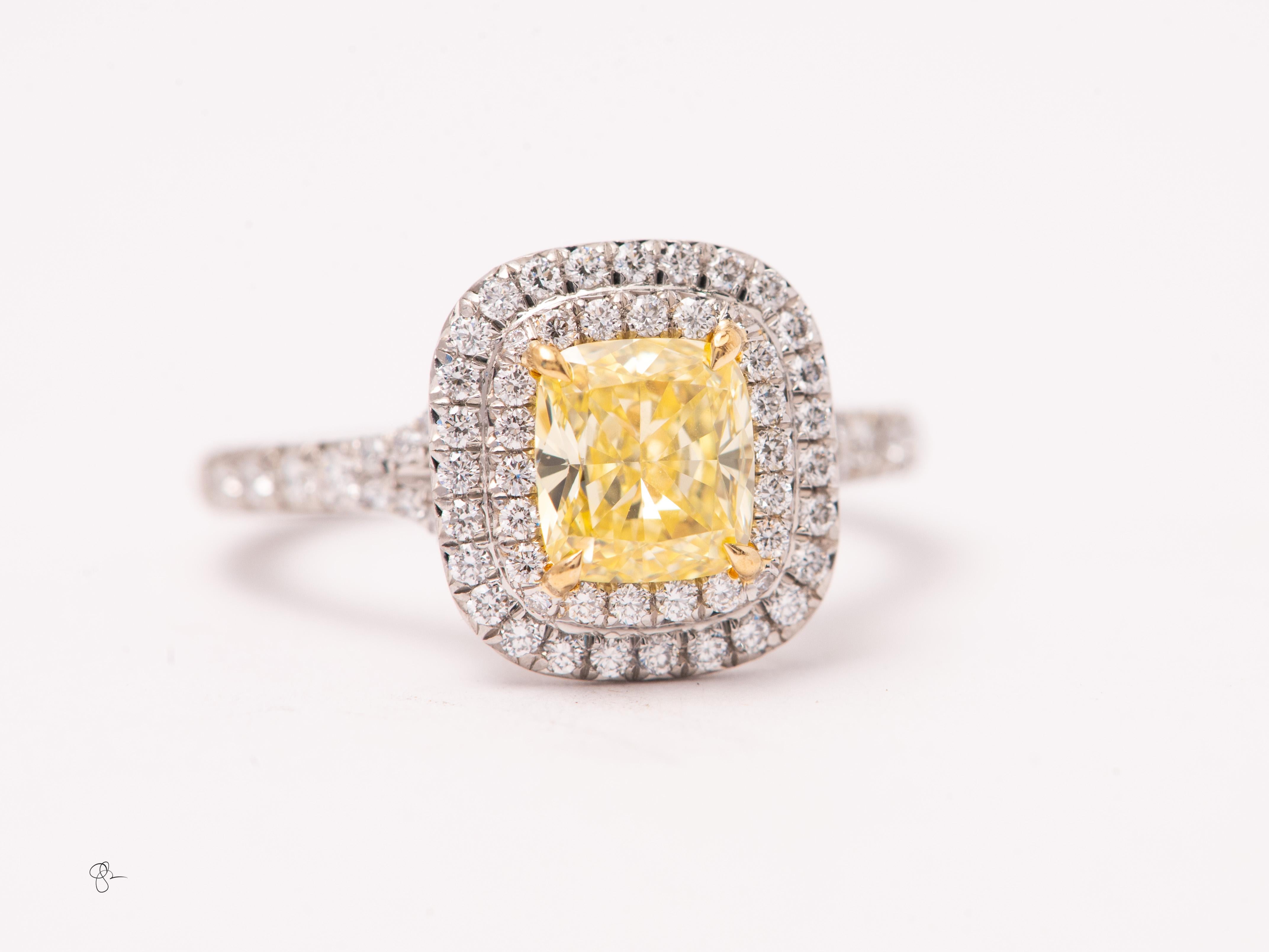 Estate Tiffany & Co. Soleste engagement ring featuring a vibrant 1.04 carat cushion-cut fancy yellow diamond framed by Tiffany’s signature double halo of white diamond melee. Approximately 0.50 carat of finely matched round brilliant diamonds accent