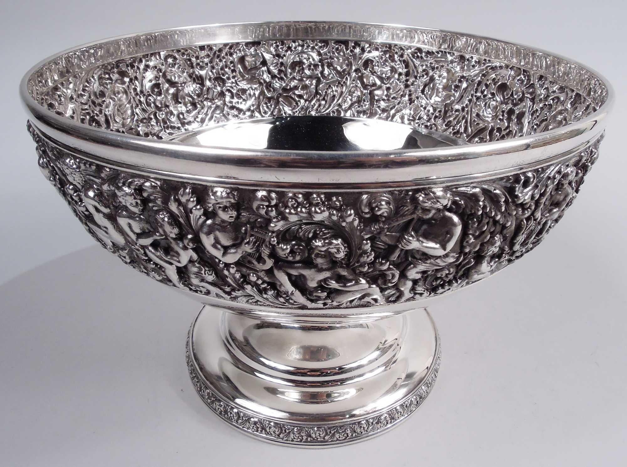 Olympian sterling silver centerpiece bowl. Made by Tiffany & Co. in New York. Curved and tapering bowl on domed foot. At top a dense repousse frieze of love-making, harp-stumming nymphs, gods, and cherubs. Foot rim has rinceaux border. A beautiful