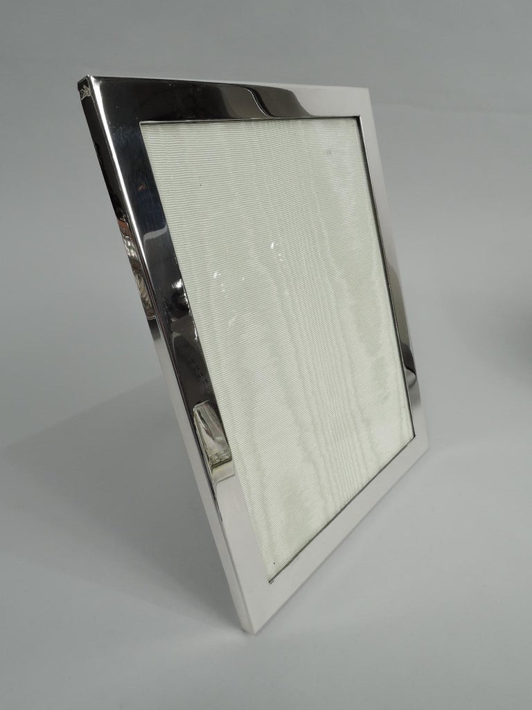 Modern sterling silver picture frame. Made by Tiffany & Co. in New York. Rectangular in plain flat surround. With glass, silk lining, and laminate back and hinged easel support for portrait (vertical) or landscape (horizontal) display. Fully marked