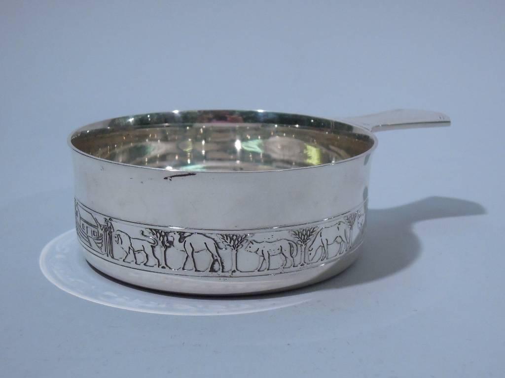 Mid-Century Modern sterling silver porringer with Noah’s Ark motif. Made by Tiffany & Co. in New York. Straight sides with flared rim and solid shaped handle. On exterior is acid-etched frieze of single-file procession: a lion, goat, bear, camel –