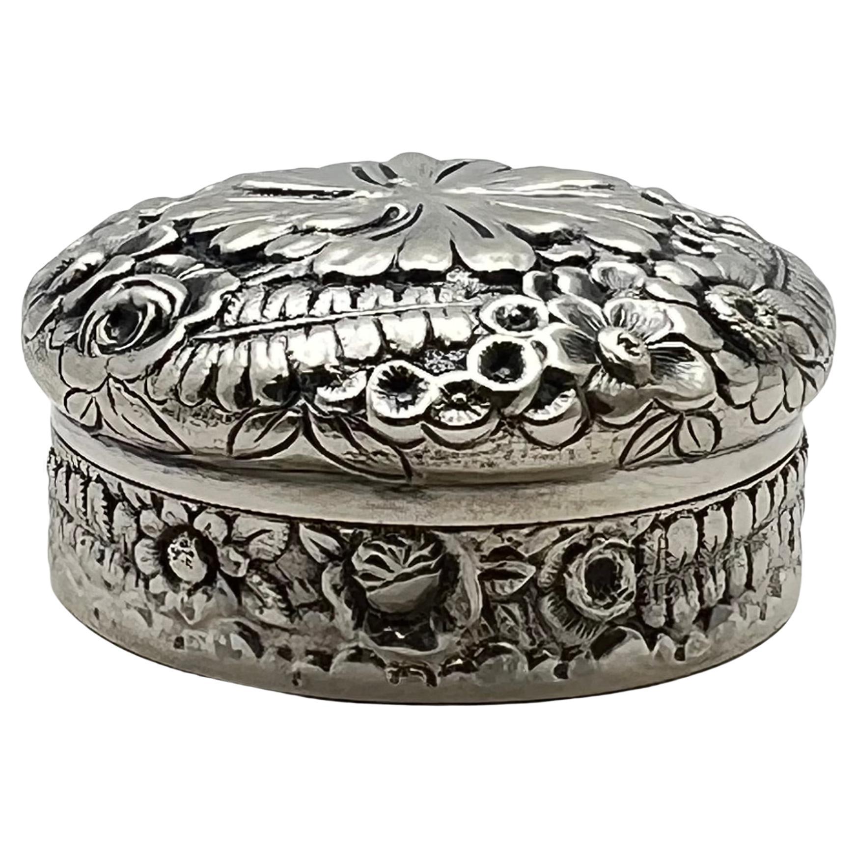 Tiffany & Co. Sterlingsilber mit Repousse-Muster, runde Pillendose mit Deckel.  Außen mit Farn- und Blumenmotiv.  Innenseite des Deckels goldfarben lackiert.  Unten markiert 'TIFFANY & CO. 7926M125  Sterling Silber