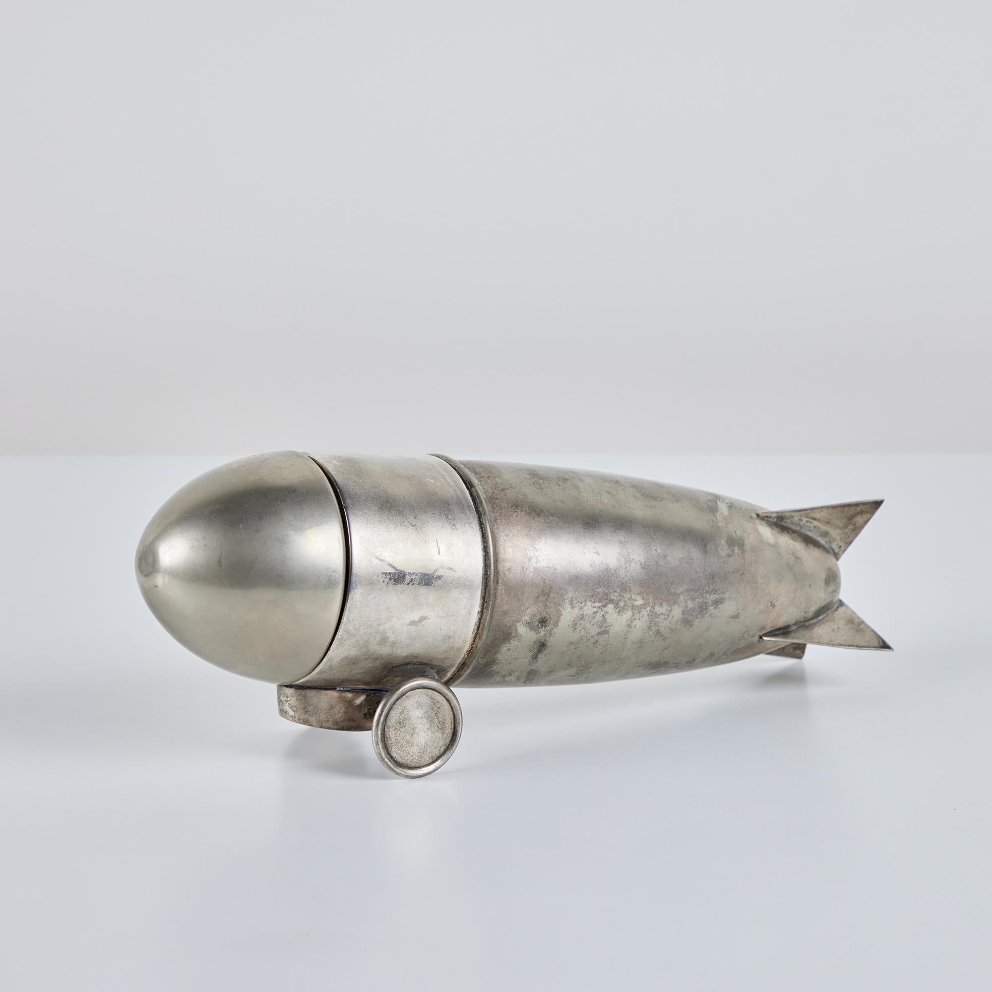 Art Deco silver plated cocktail shaker, circa 1930s, USA, in the style of Tiffany Studios. The shaker features a zeppelin body with three sections; a removable lid, strainer and vessel.

Dimensions
12