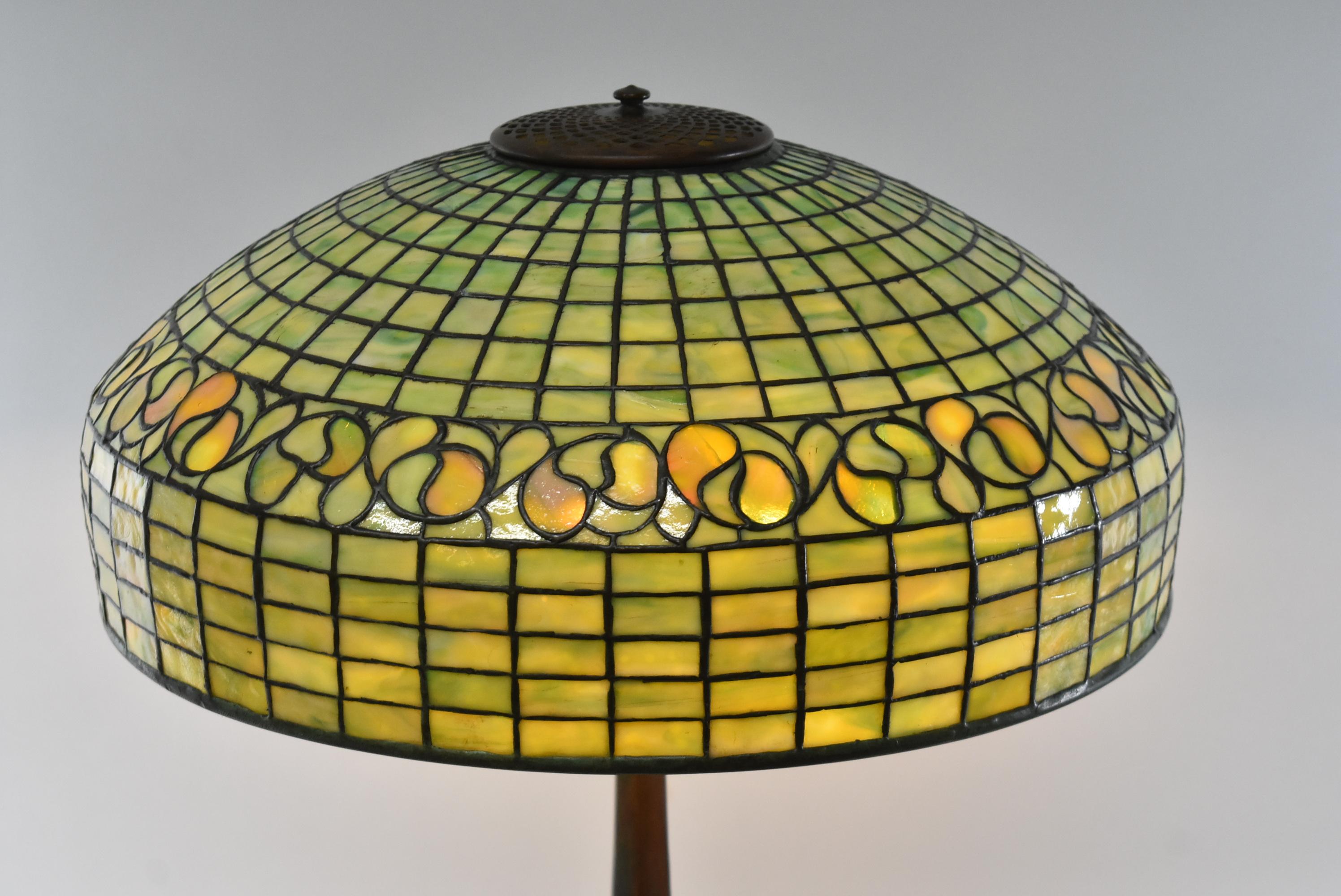Absolutely stunning leaded glass lamp by Tiffany Studios New York in green glass with a lemon leaf pattern around the border. The dense opalescent multi-tone green glass shade measures 18
