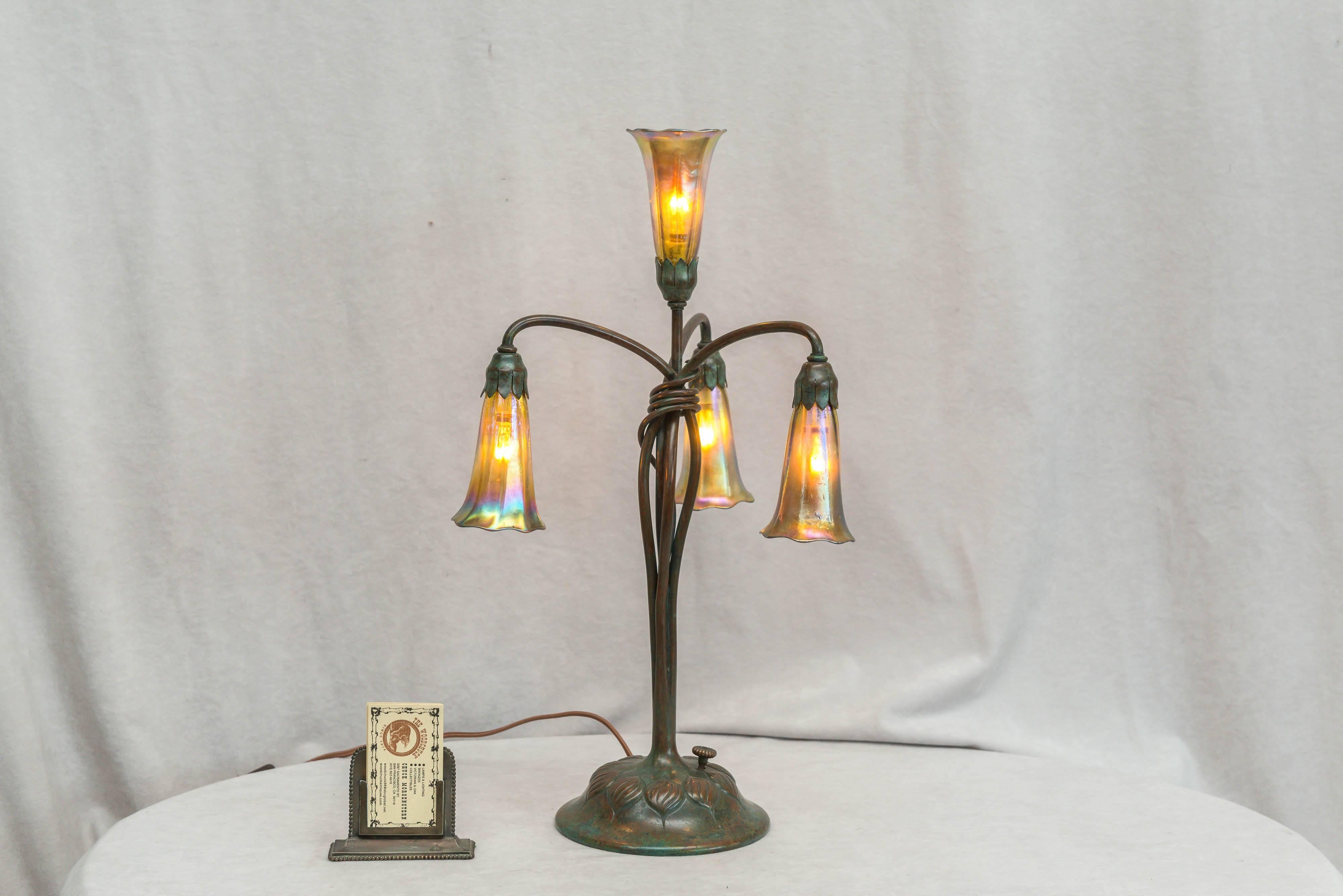 One of the more popular and desirable lamps by the renown Tiffany Studios, is their lily lamps. The base and all the shades are properly signed. The base has that beautiful verdigris patina, and the shades are of course all handblown. There is some