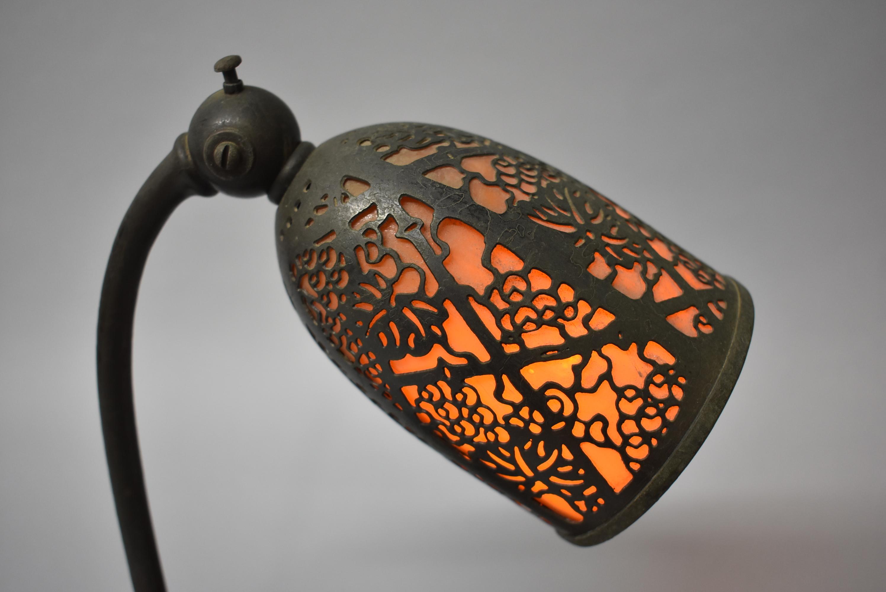 Antique Tiffany Studios bronze desk lamp with amber slag glass shade covered in filigree grapevine pattern. Single socket. Marked on the bottom #552. Shade adjusts.