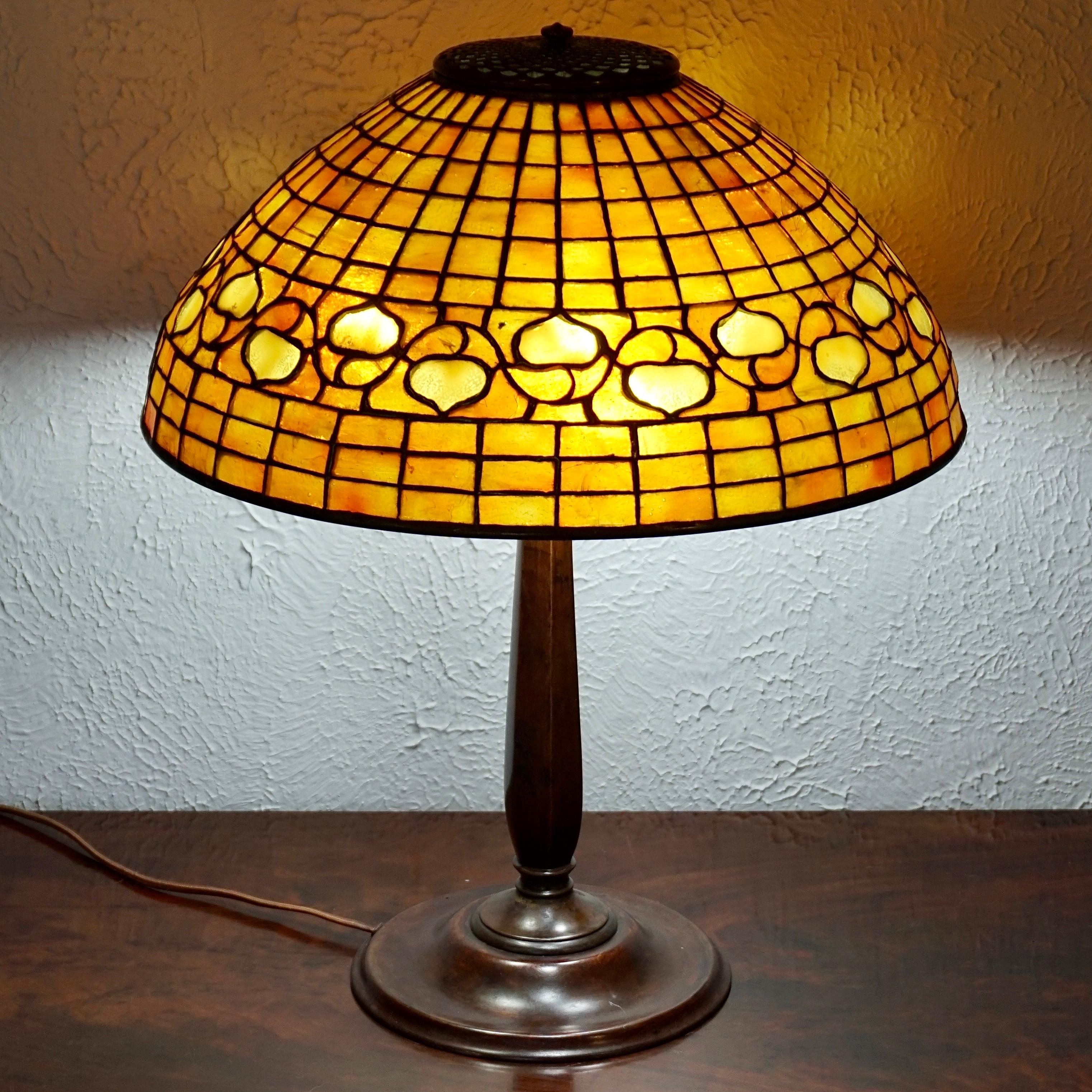 A warm and wonderful Art Nouveau Tiffany Studios table lamp, circa 1910

The stained glass Tiffany Studios shade emits vibrant orange and yellow glow from the monochromatic panels of glass. The pattered acorns with geometric surrounding glass sit