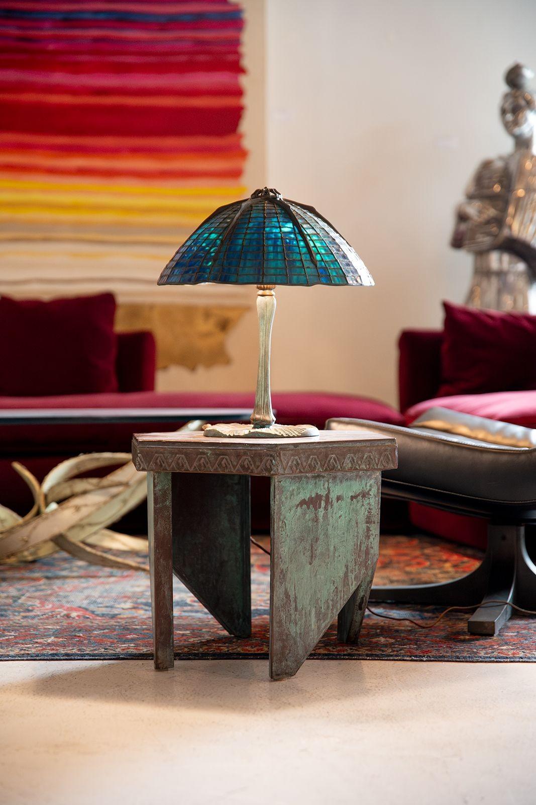 Very old, heavy, cast bronze spider lamp with beautiful verdigris patina and blue stained glass shade.
This lamp was acquired from an estate in upstate New York. Both the bottom of the lamp and the shade are stamped with the embossed Tiffany Studios