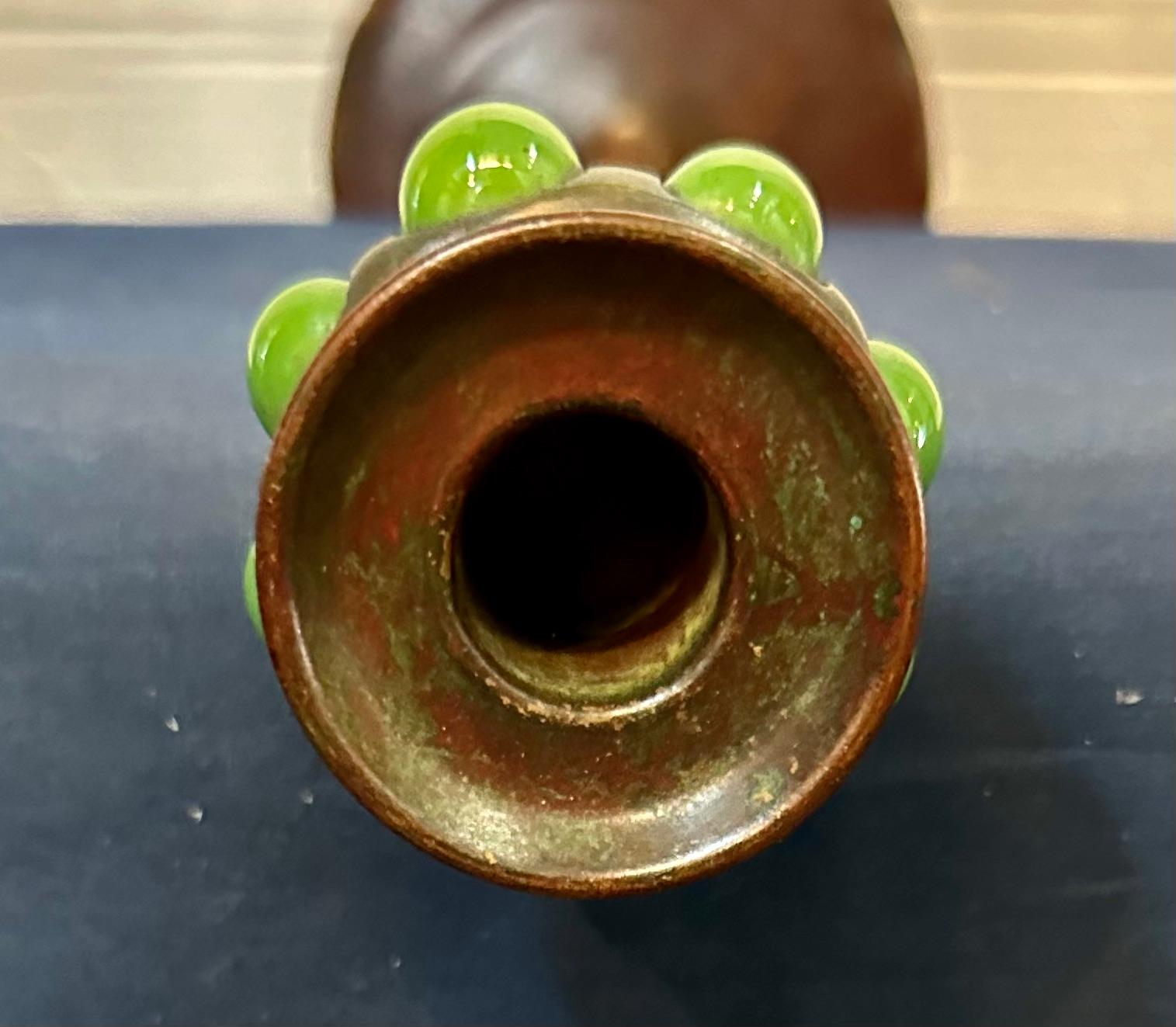 Questo candeliere vintage in bronzo patinato dei Tiffany Studios dell'inizio del XX secolo è dotato di una coppa per candele contenente vetro verde soffiato ovoidale. Questo candeliere è in condizioni eccellenti. Sulla base c'è il timbro 