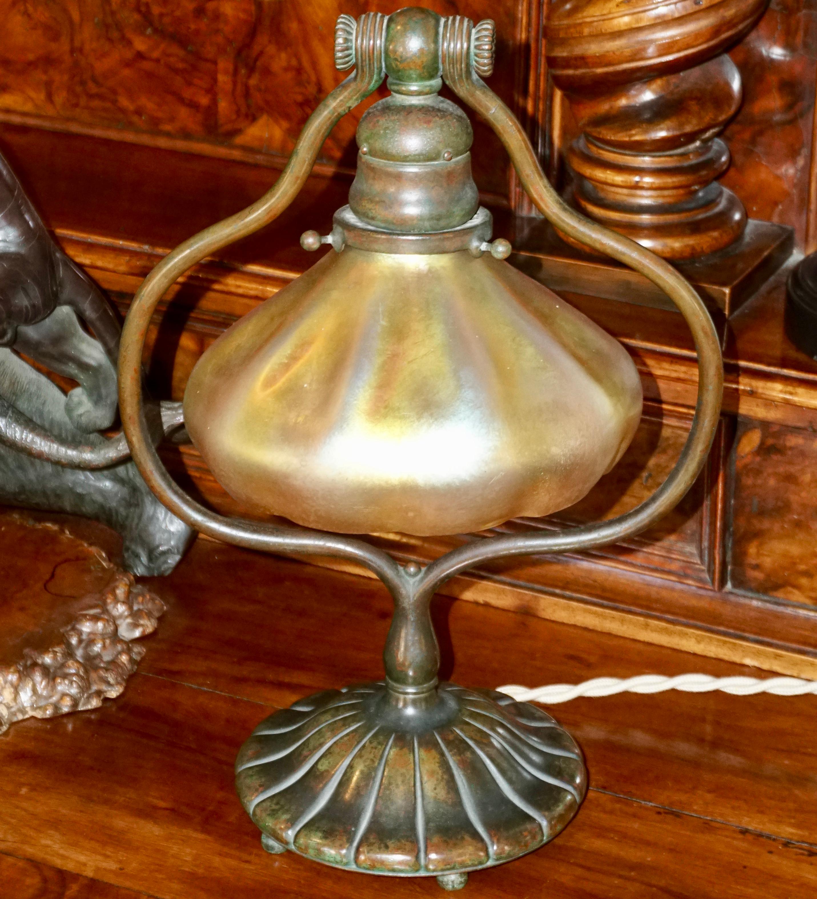 Eine spektakuläre:: aber einfache Tiffany Studios Bronze Schreibtisch oder Tischlampe mit seiner ursprünglichen schillernden Favrile Gold Schatten. Der Sockel mit verschnörkelter:: bauchiger Harfe steht auf einem kreisförmigen:: kannelierten