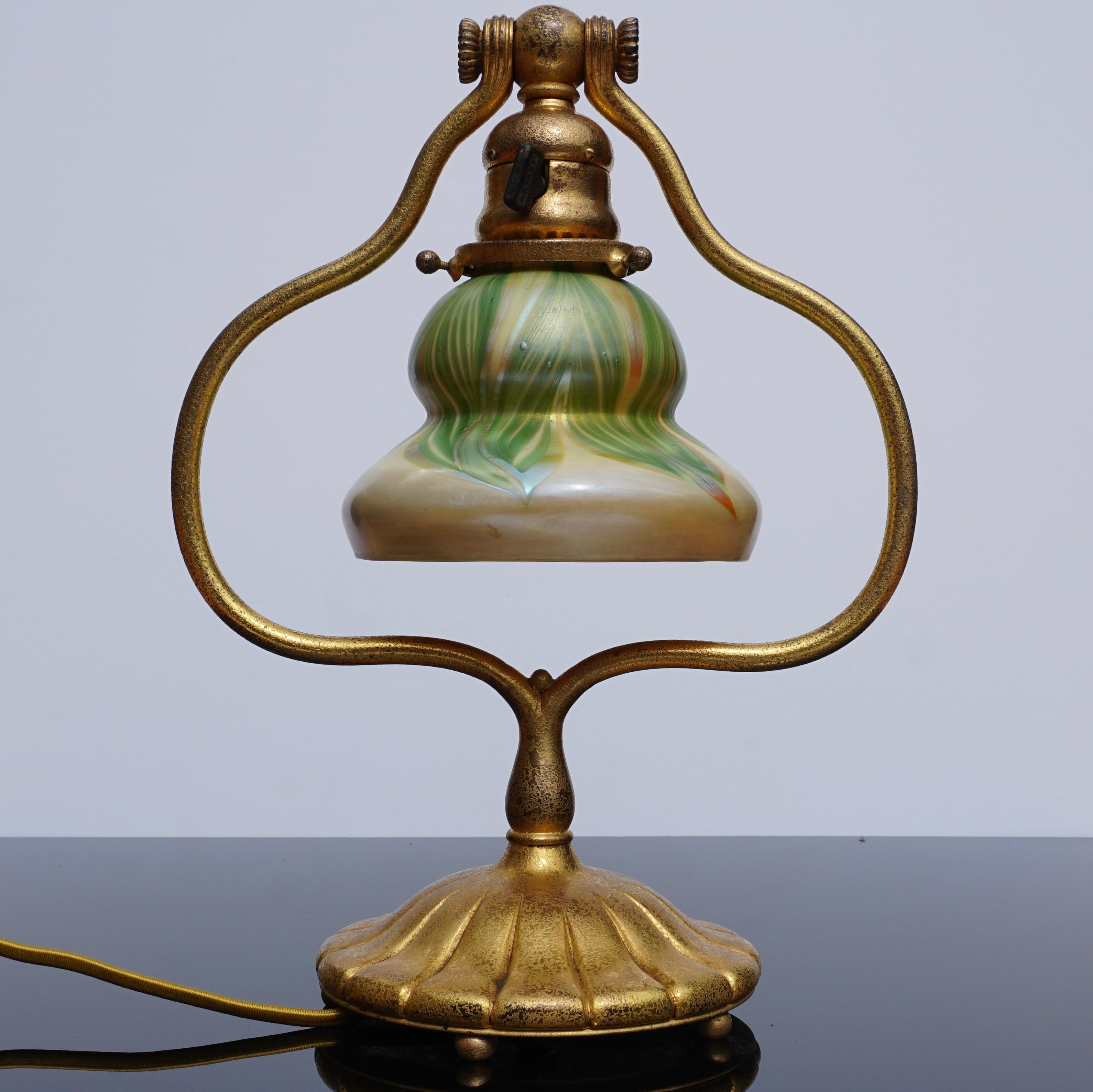 A delightful Tiffany Studios New York 419 bronze harp Art Nouveau table or desk lamp with a stunning L.C.T signed pull feathered favrile and gold iridescent glass shade. The bronze base with textured gilt gold patina. This lamp has no issues and is