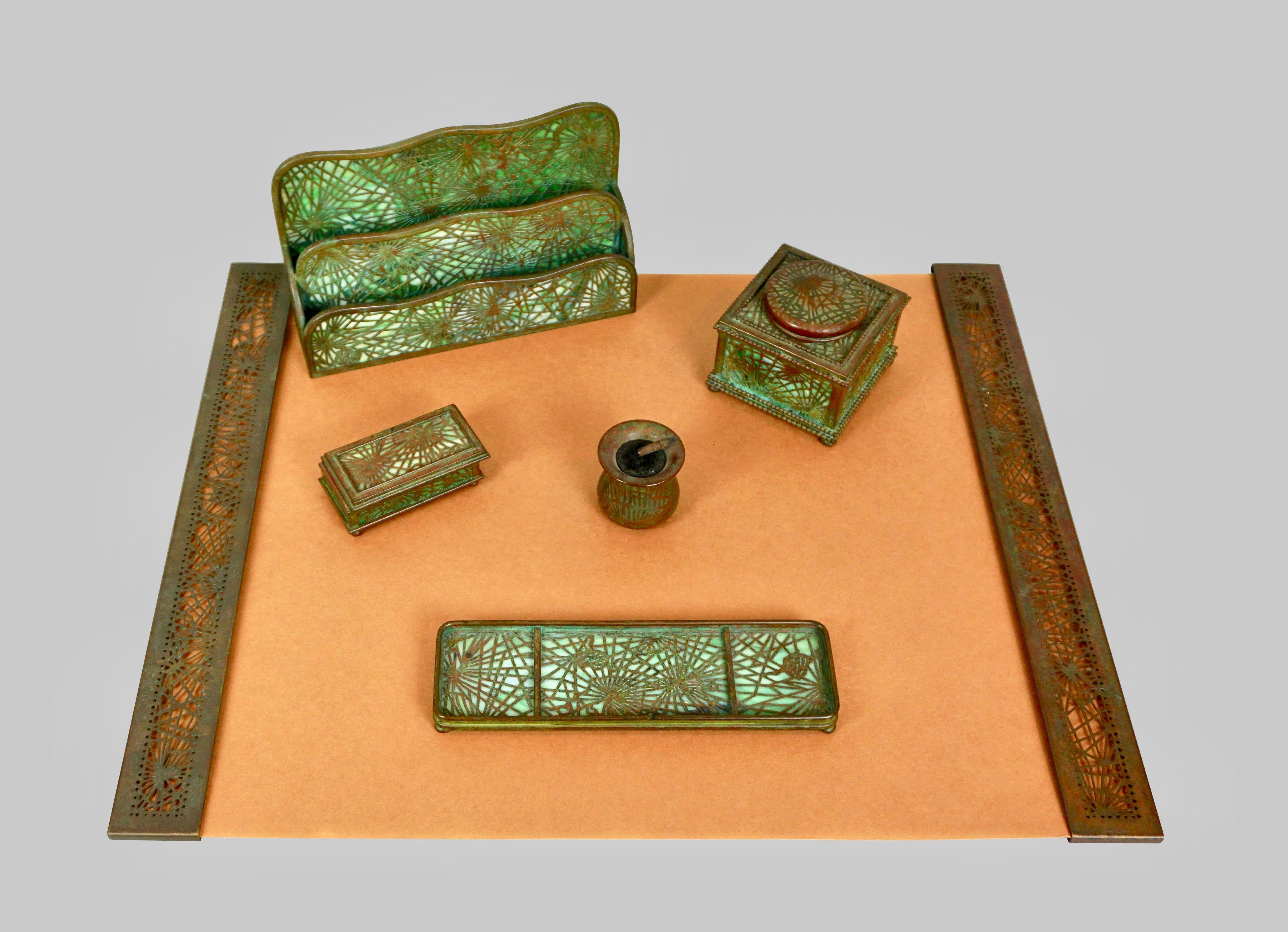A 6 piece Tiffany Studios pine needle pattern fully signed bronze and glass desk set consisting of blotter ends, pen tray, inkwell, letter tray, nib cleaner and stamp box. The pine needle pattern was one the more popular of the Tiffany Studios'