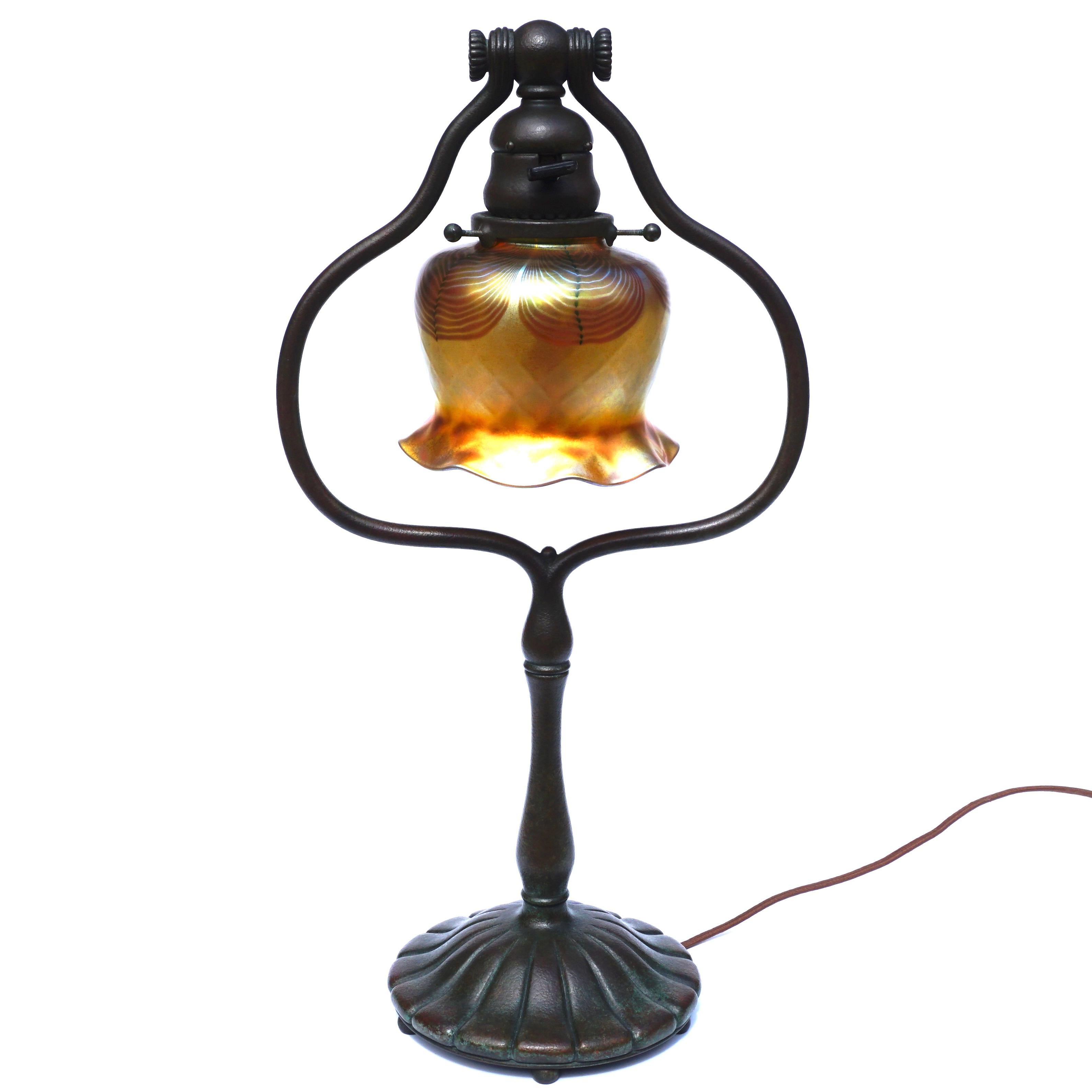 A wonderful patinated bronze and L.C.T. quilted and feather pulled favrile lamp that fits anywhere. At 18 Inches tall; this lamp is medium sized and would accommodate anywhere from the bedroom to the living room and in the office. The rare decorated