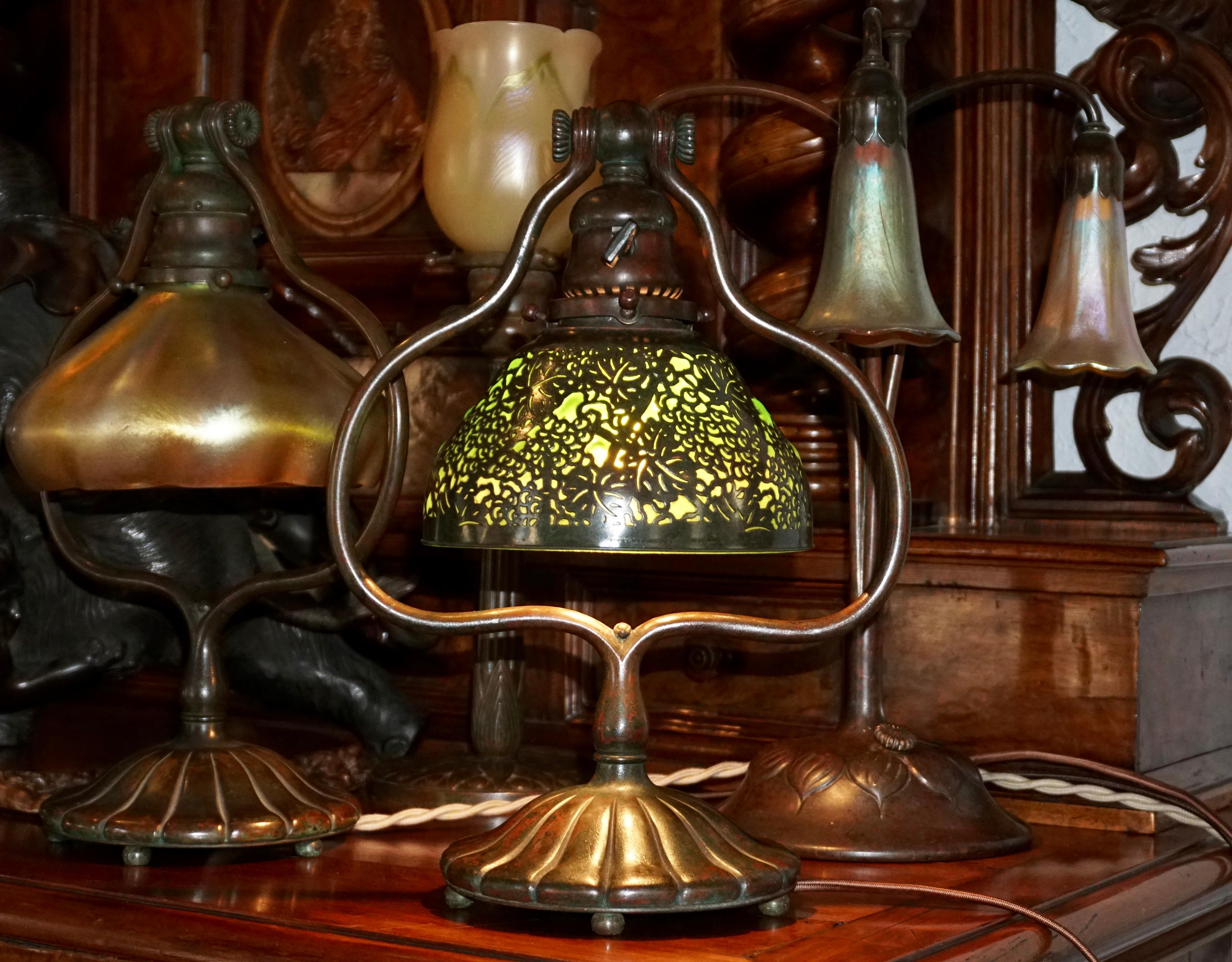 This is a rare infused molded glass and bronze Tiffany Studios Grapevine green glass shade in perfect condition. The TSNY bronze harp lamp base and the shade have a beautiful green red and brown patina. This lamp is perfect with original GE switch