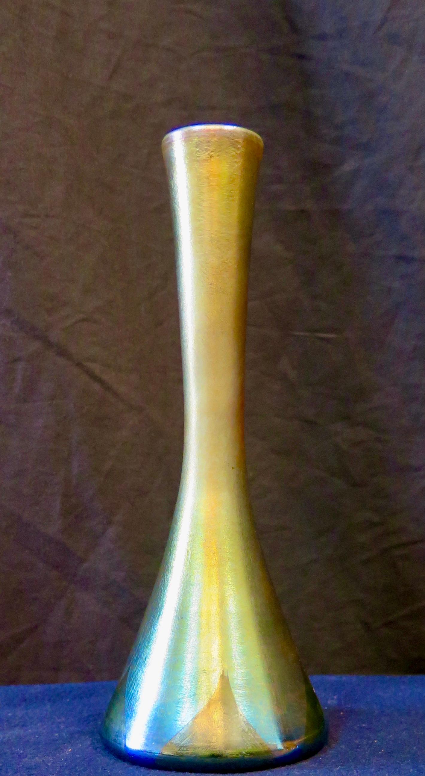 This vintage early 20th century Tiffany Studios, New York favrile art glass vase is numbered “3335” “J” & signed “L. C. Tiffany Favrile”. The vase has an elegant slender form with vivid coloration that is accented with iridescent solid “triangles”