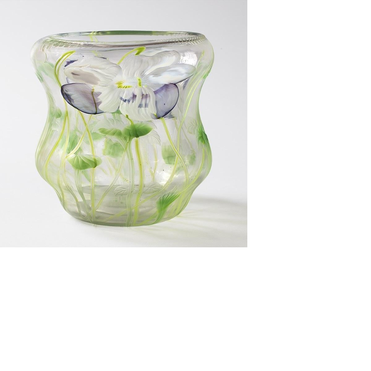 An intaglio carved translucent vase by Tiffany Studios New York. The vase is decorated with purple and white flowers and green leafy stems on a clear ground. Leaves, some green and others clear, are carved into the vase.

A similar vase is